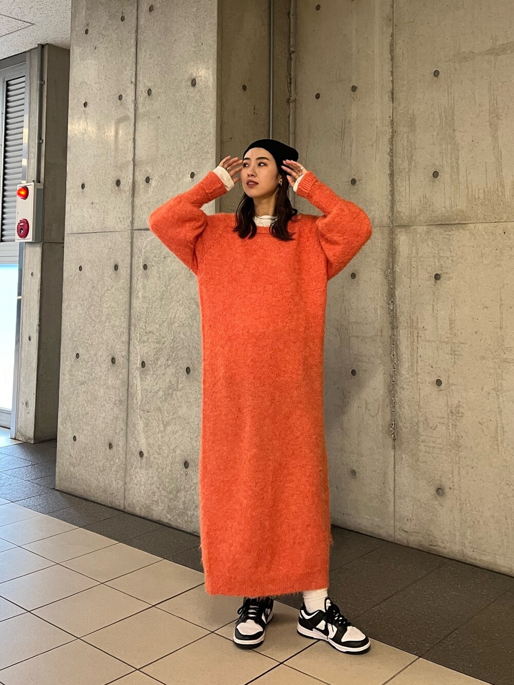 オレンジ系のワンピース、ブラック系のニットキャップ/ビーニーを着用したレディースの冬コーディネートの2枚目の写真