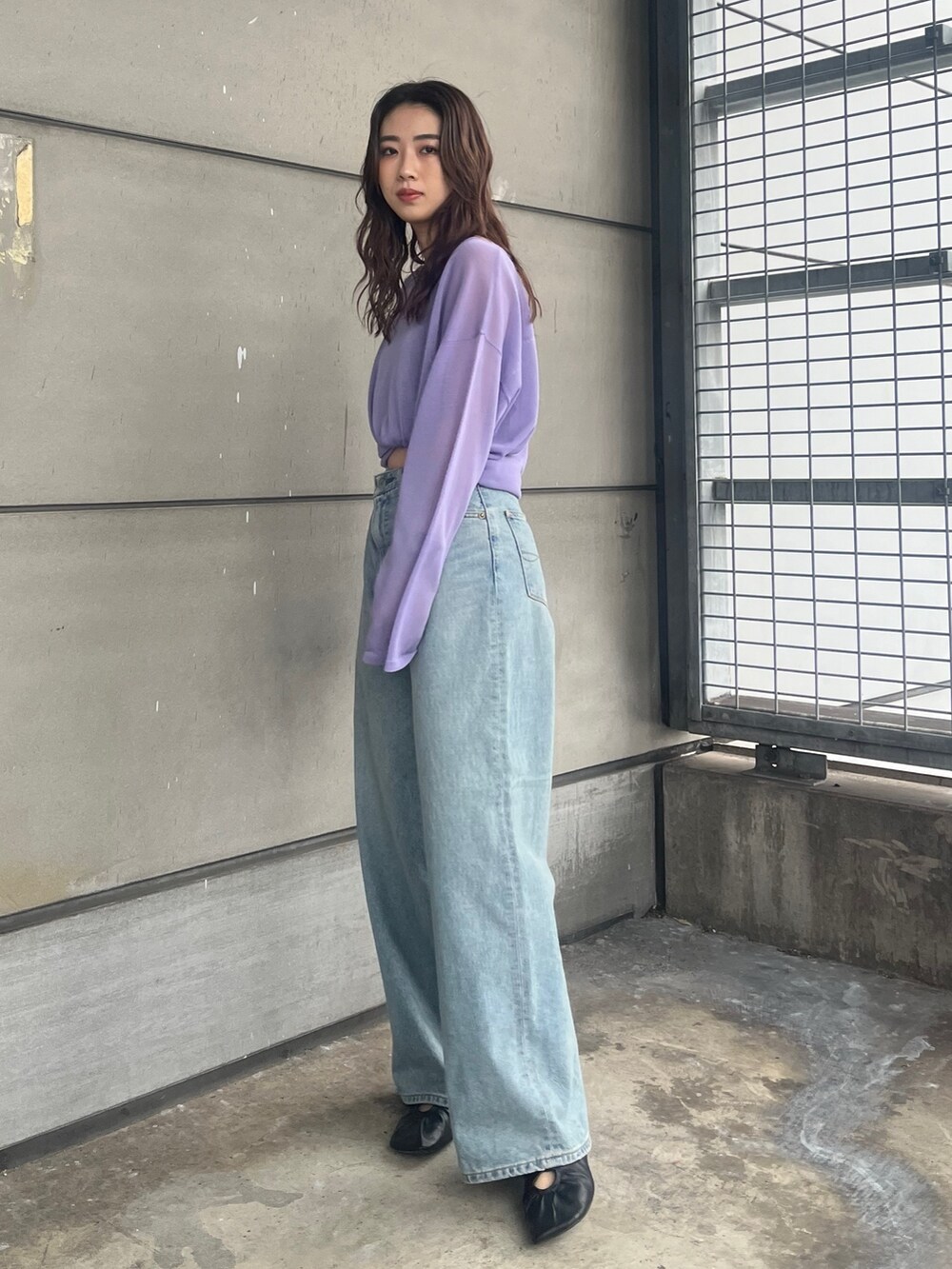 パープル系のニット/セーター、ブルー系のデニムパンツを着用したレディースの春コーディネートの2枚目の写真