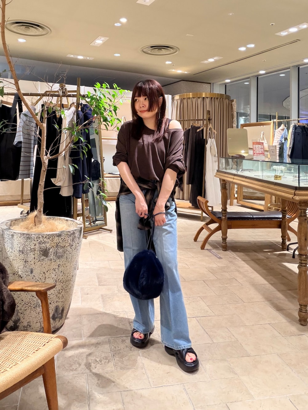ブルー系のデニムパンツ、ベージュ系のトートバッグ、ブラック系のサンダルを着用したレディースの夏コーディネートの3枚目の写真