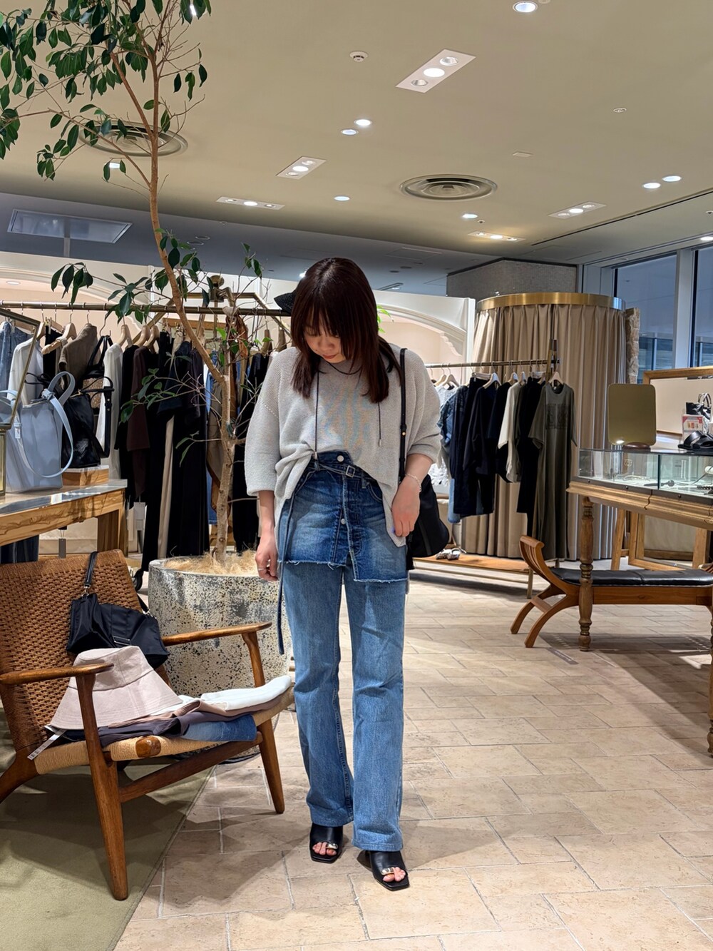 ブルー系のデニムスカート、シルバー系のニット/セーター、ブラック系のトートバッグを着用したレディースの春コーディネートの5枚目の写真