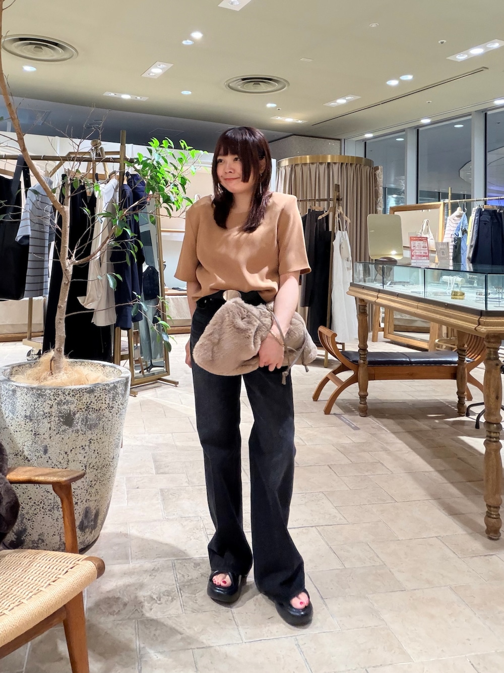 ベージュ系のトートバッグ、ブラック系のデニムパンツ、ブラック系のサンダルを着用したレディースの夏コーディネートの3枚目の写真