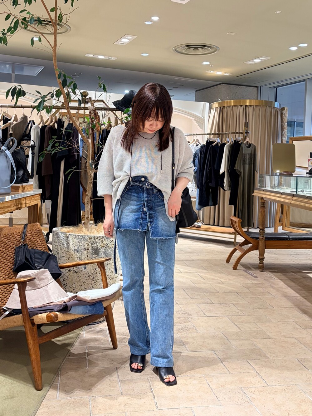 ブルー系のデニムスカート、シルバー系のニット/セーター、ブラック系のトートバッグを着用したレディースの春コーディネートの2枚目の写真