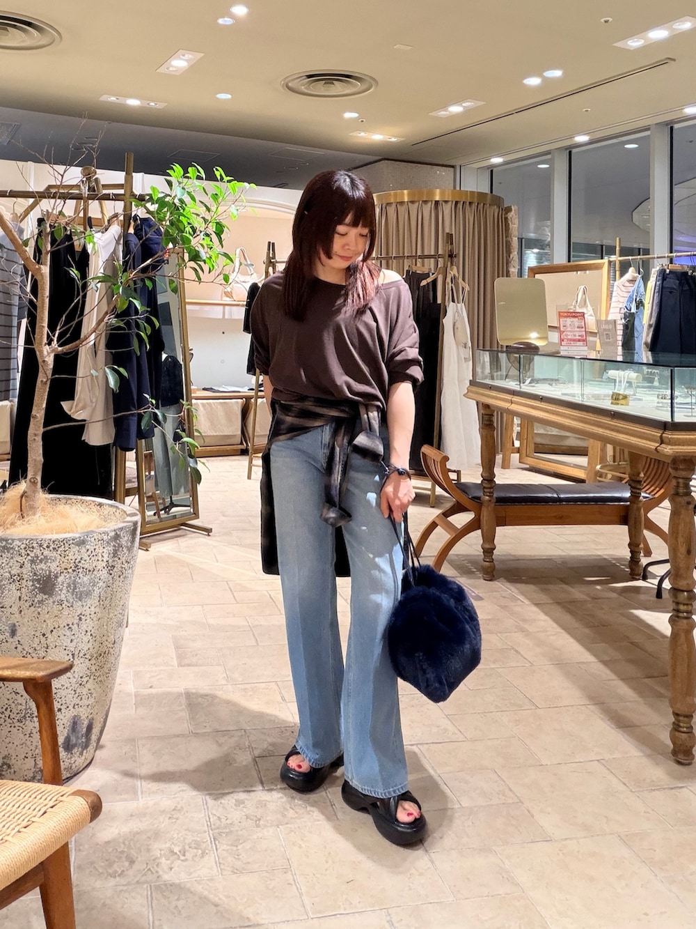 ブルー系のデニムパンツ、ベージュ系のトートバッグ、ブラック系のサンダルを着用したレディースの夏コーディネートの2枚目の写真