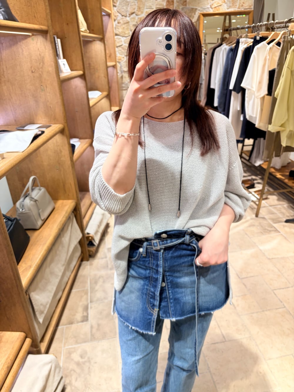 ブルー系のデニムスカート、シルバー系のニット/セーター、ブラック系のトートバッグを着用したレディースの春コーディネートの4枚目の写真