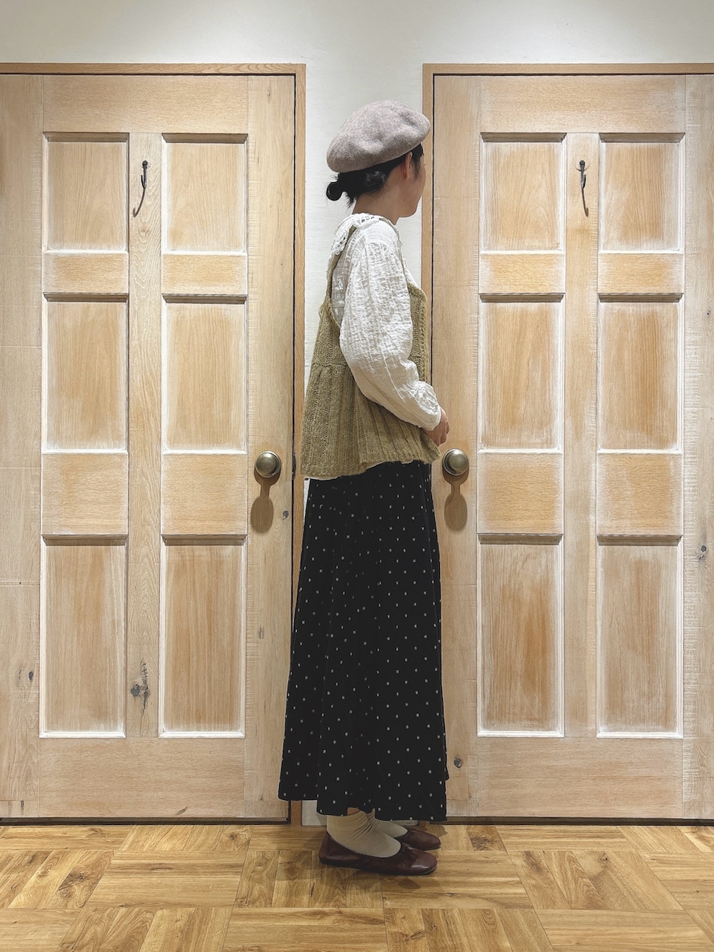 イエロー系のニット/セーター、ホワイト系のシャツ/ブラウス、ブラック系のスカートを着用したレディースの秋コーディネートの2枚目の写真