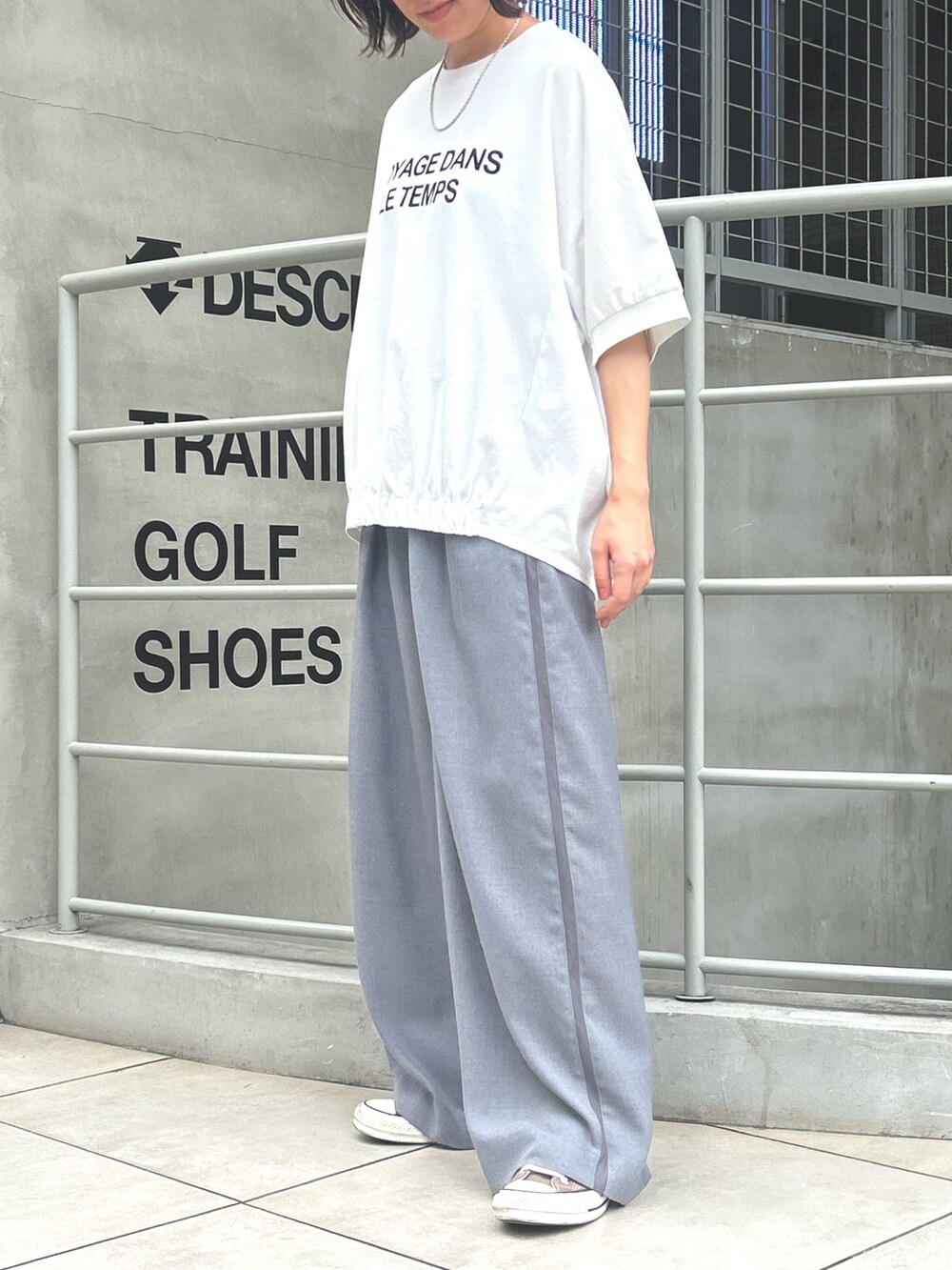 グレー系のスラックス、ホワイト系のTシャツ/カットソーを着用したレディースの秋コーディネートの2枚目の写真