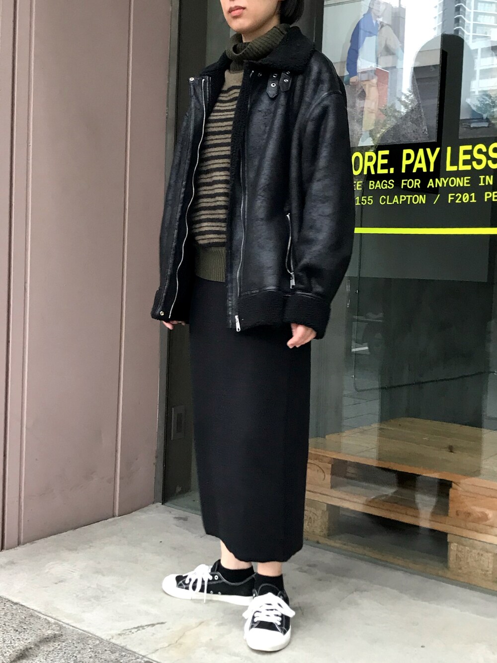 グリーン系のニット/セーター、ブラック系のブルゾン、ブラック系のスカートを着用したレディースの秋コーディネートの2枚目の写真