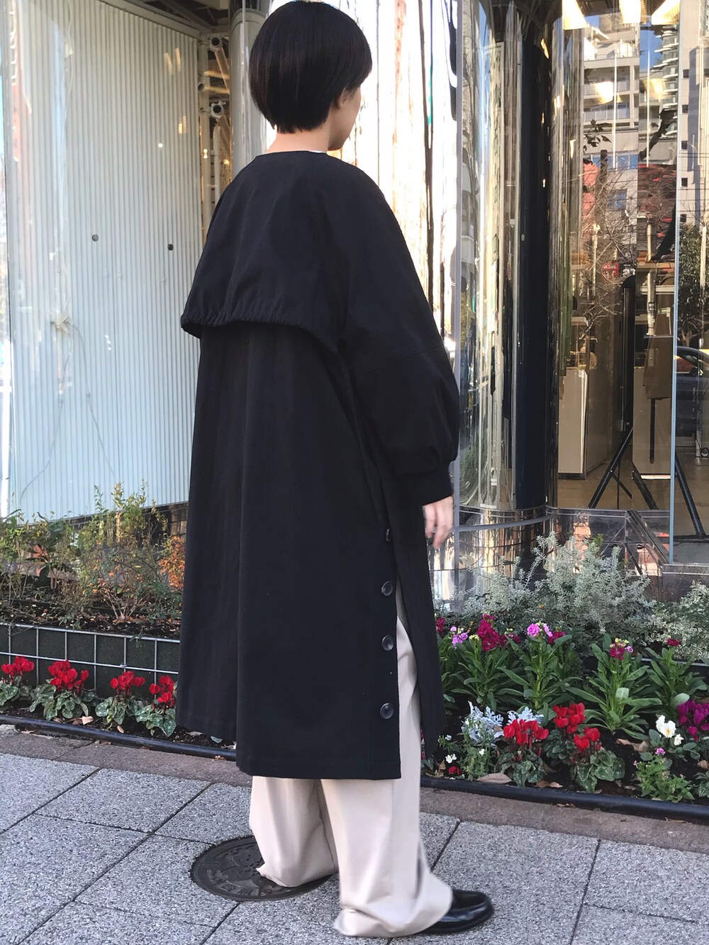 ブラック系のノーカラーコート、ベージュ系のスラックスを着用したレディースの冬コーディネートの2枚目の写真