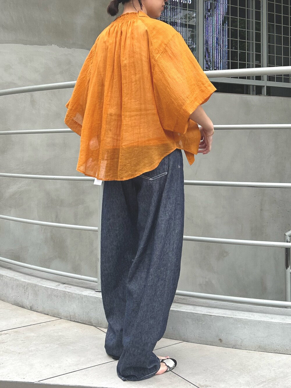 ブルー系のデニムパンツ、オレンジ系のタンクトップ、オレンジ系のシャツ/ブラウスを着用したレディースの春コーディネートの2枚目の写真