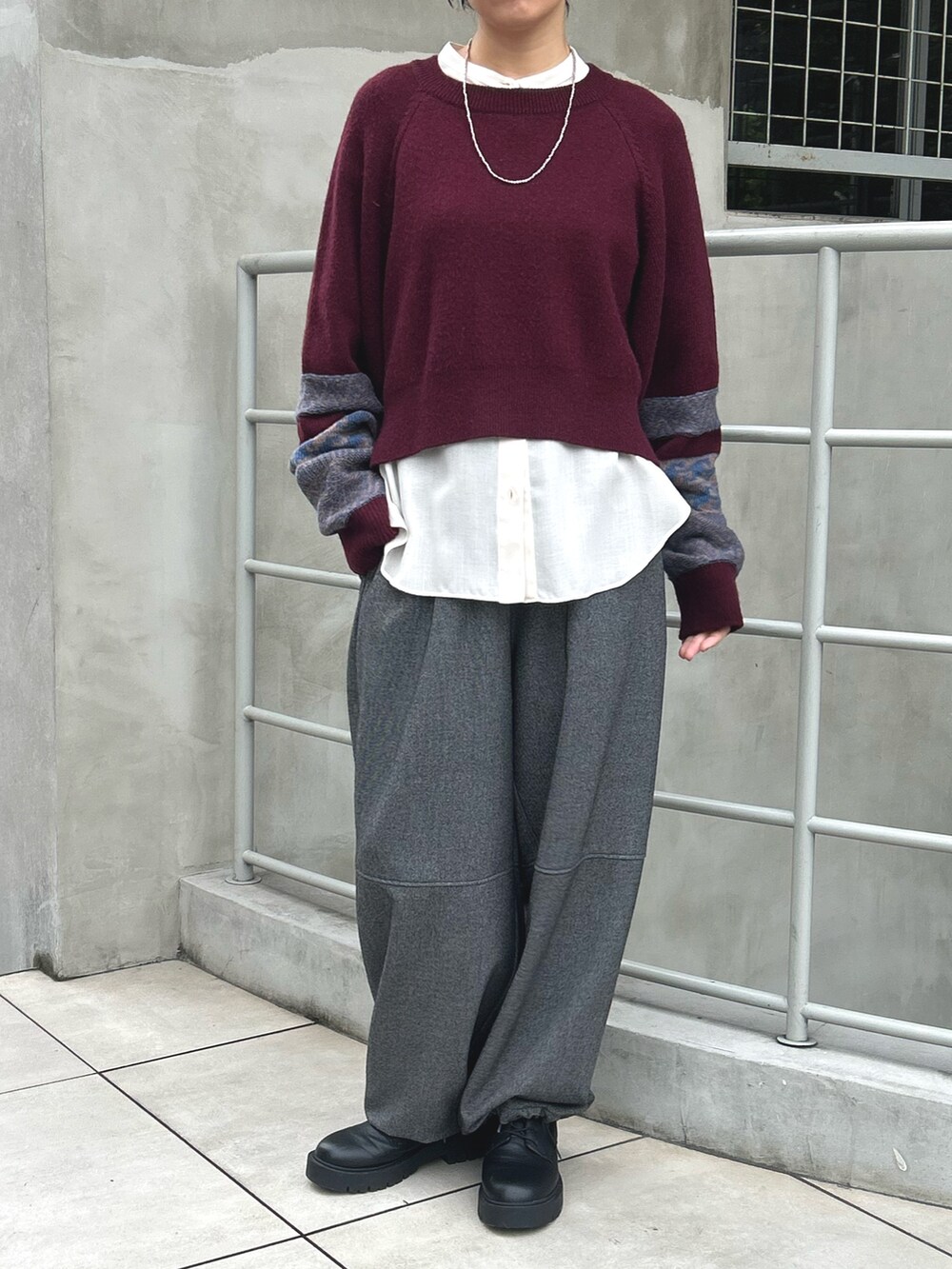 グレー系のその他パンツ、レッド系のニット/セーター、ホワイト系のシャツ/ブラウスを着用したレディースの秋コーディネートの2枚目の写真