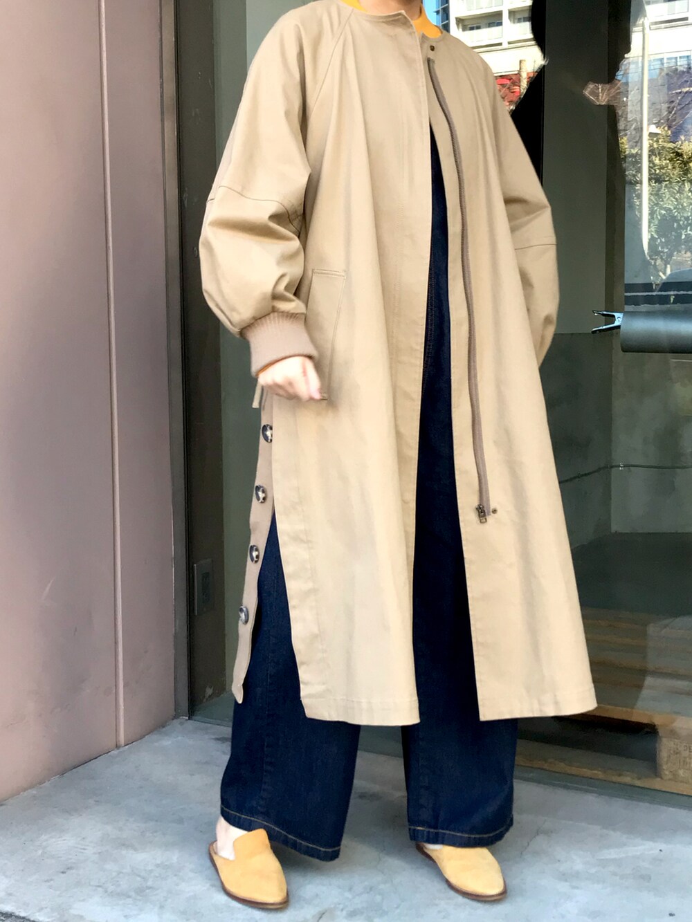 ベージュ系のノーカラーコートを着用したレディースの冬コーディネートの2枚目の写真