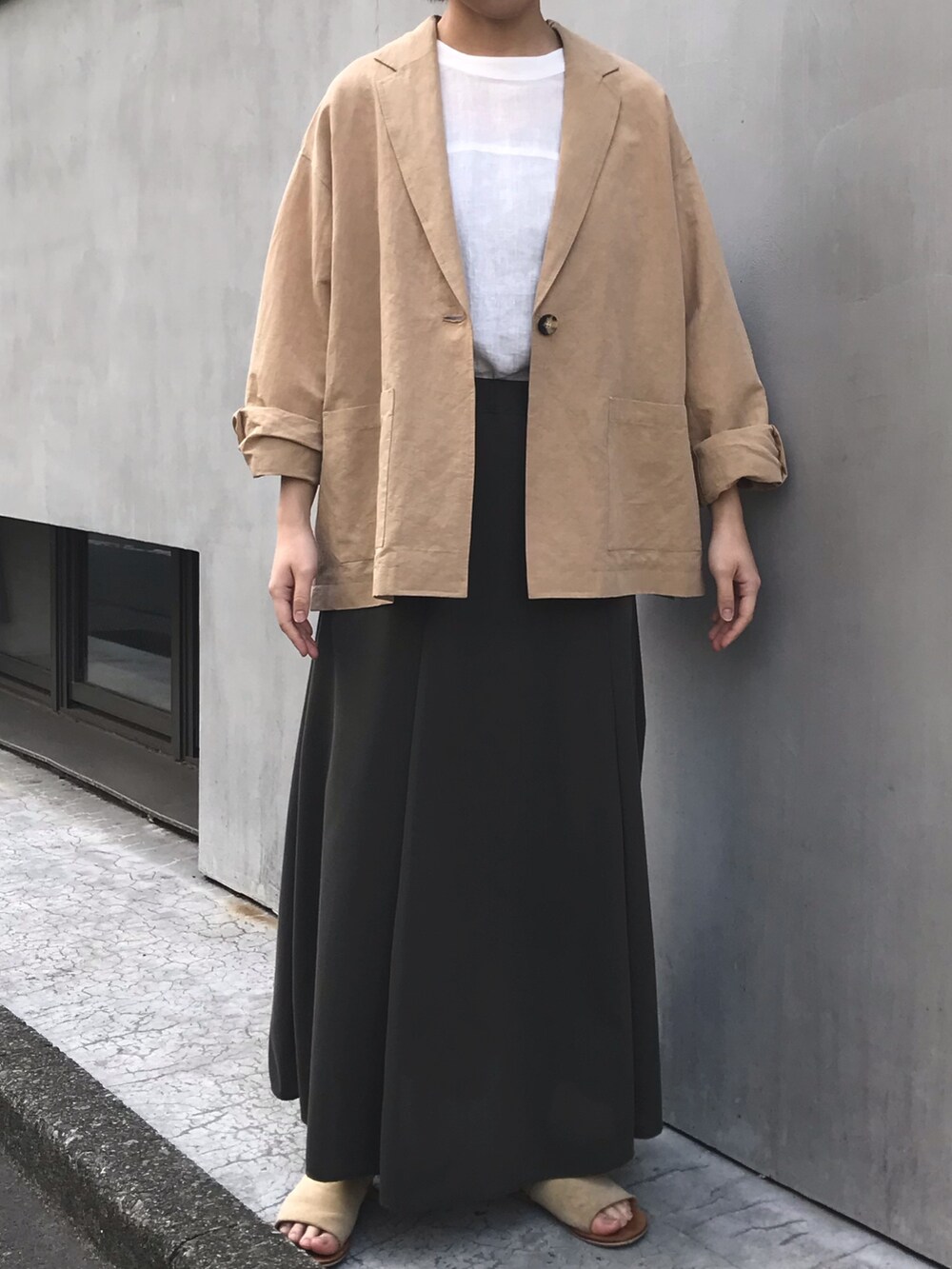 ベージュ系のテーラードジャケット、ホワイト系のシャツ/ブラウス、グリーン系のスカートを着用したレディースの春コーディネートの2枚目の写真