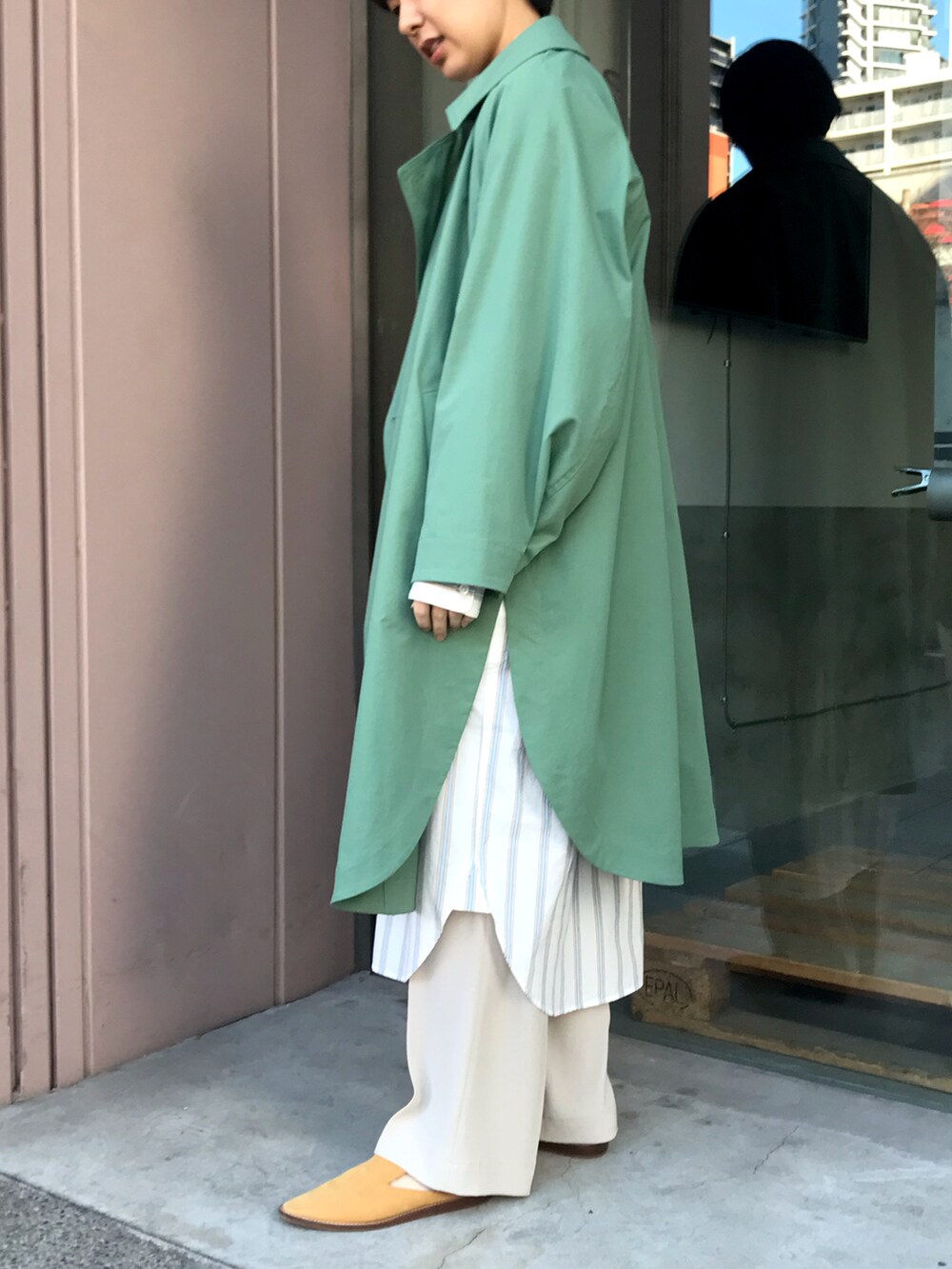グリーン系のトレンチコートを着用したレディースの冬コーディネートの2枚目の写真