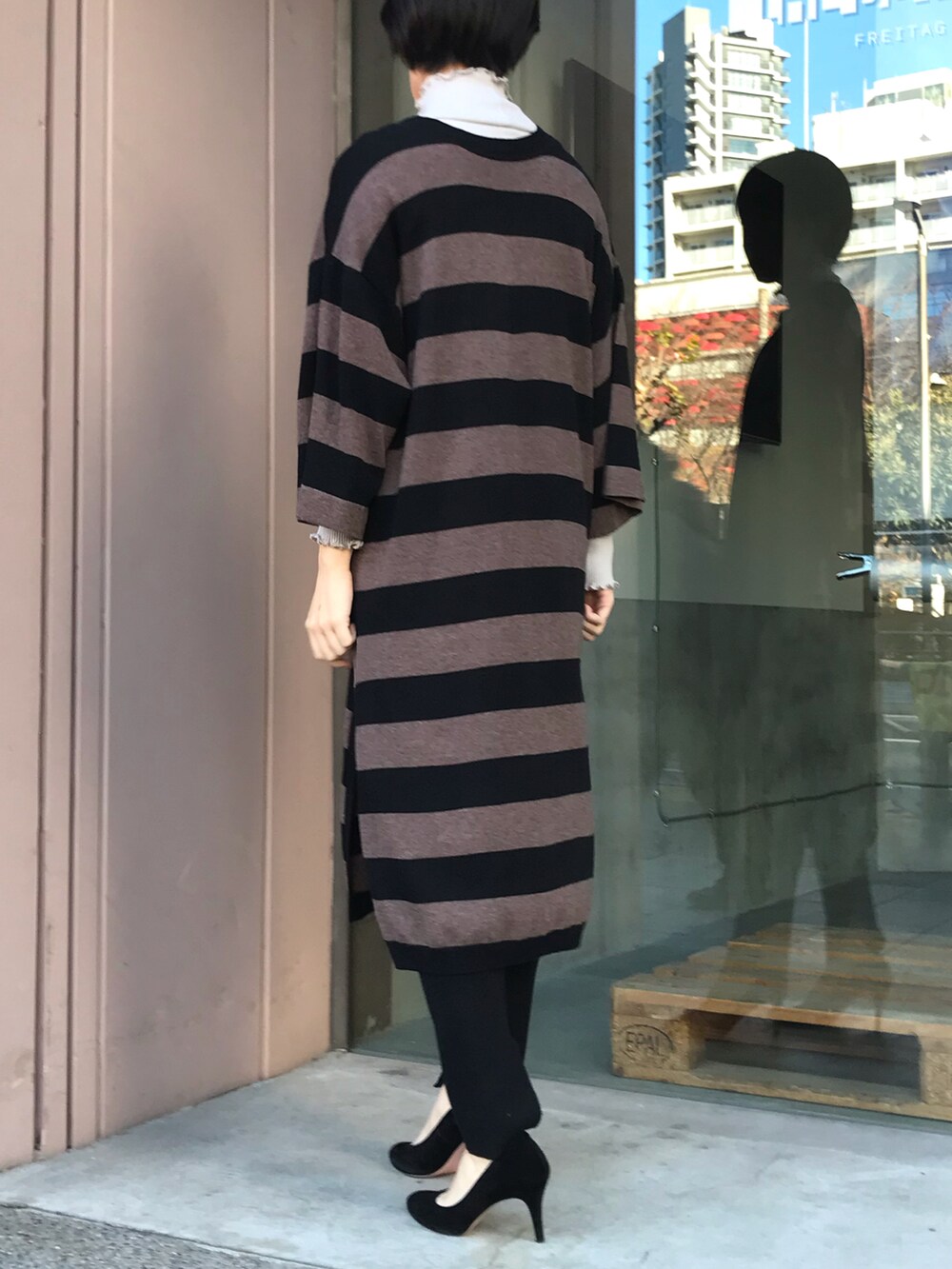 ブラック系のニット/セーター、ベージュ系のTシャツ/カットソー、ブラック系のパンツを着用したレディースの冬コーディネートの2枚目の写真