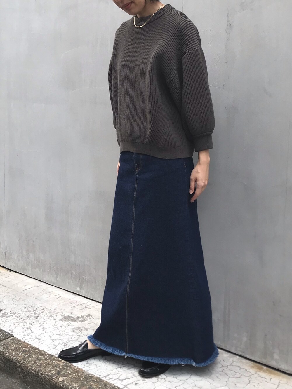 ブルー系のデニムスカート、グリーン系のニット/セーターを着用したレディースの秋コーディネートの2枚目の写真