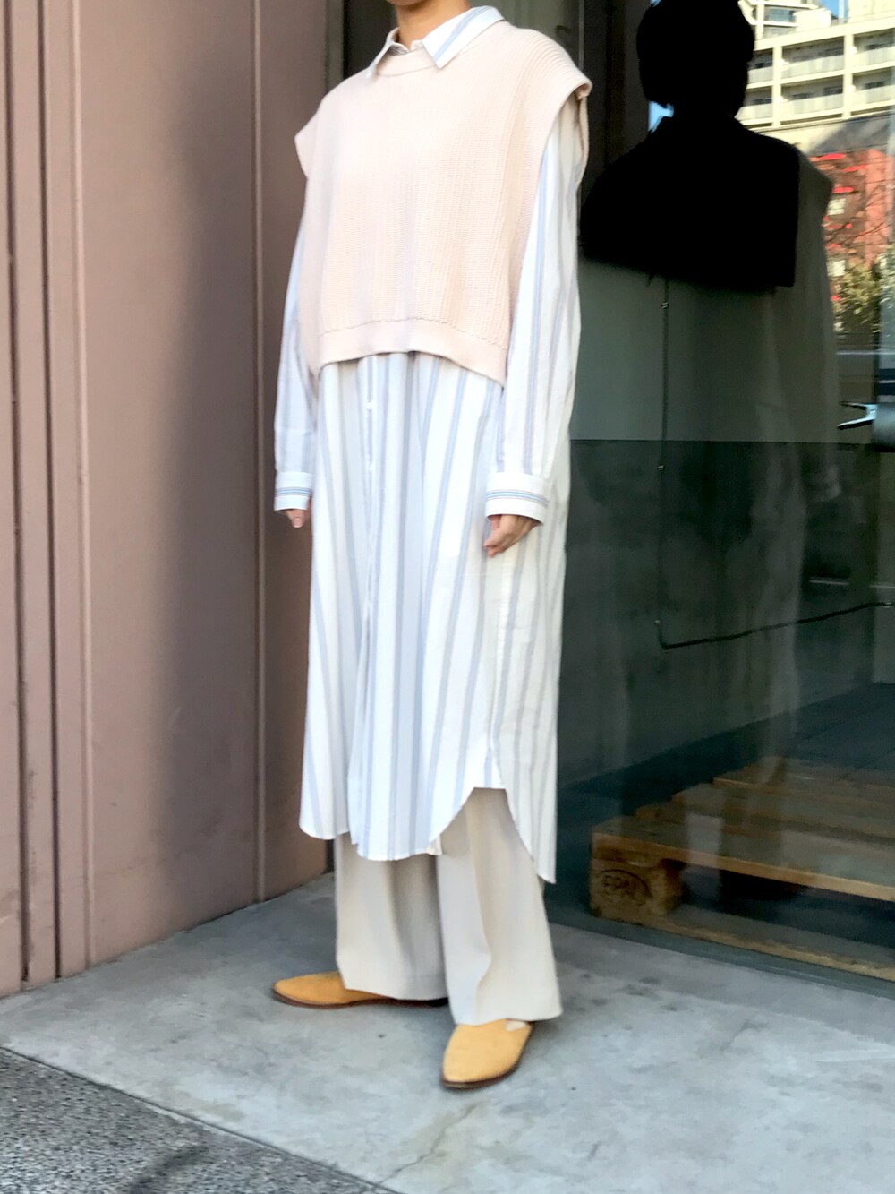 ホワイト系のシャツワンピース、ベージュ系のベストを着用したレディースの冬コーディネートの2枚目の写真