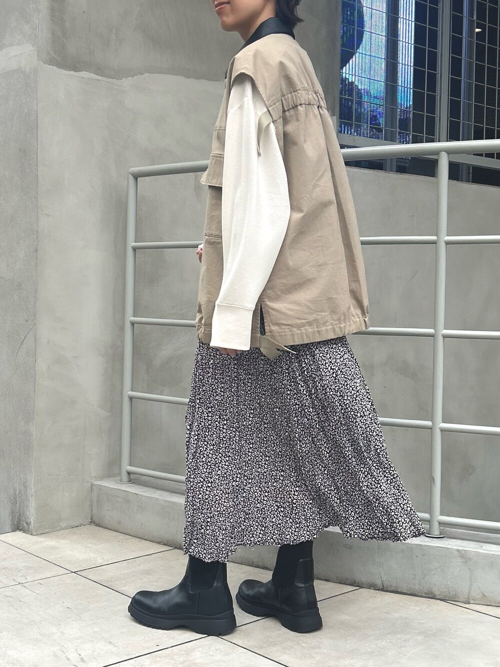 ブラック系のスカート、ベージュ系のブルゾン、ホワイト系のTシャツ/カットソーを着用したレディースの秋コーディネートの2枚目の写真