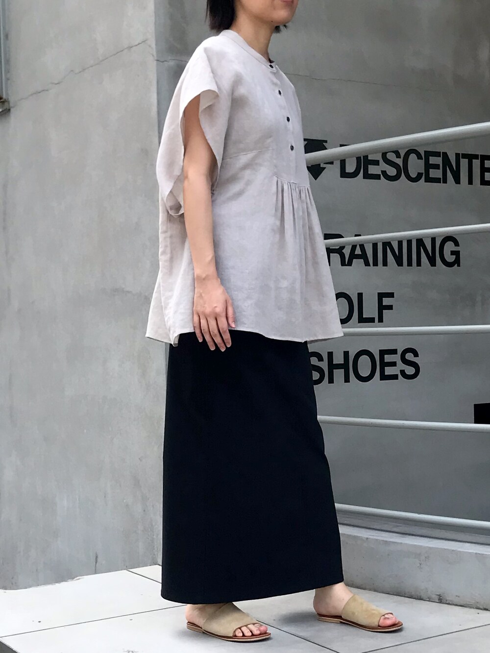 ブラック系のスカート、ベージュ系のシャツ/ブラウスを着用したレディースの夏コーディネートの2枚目の写真