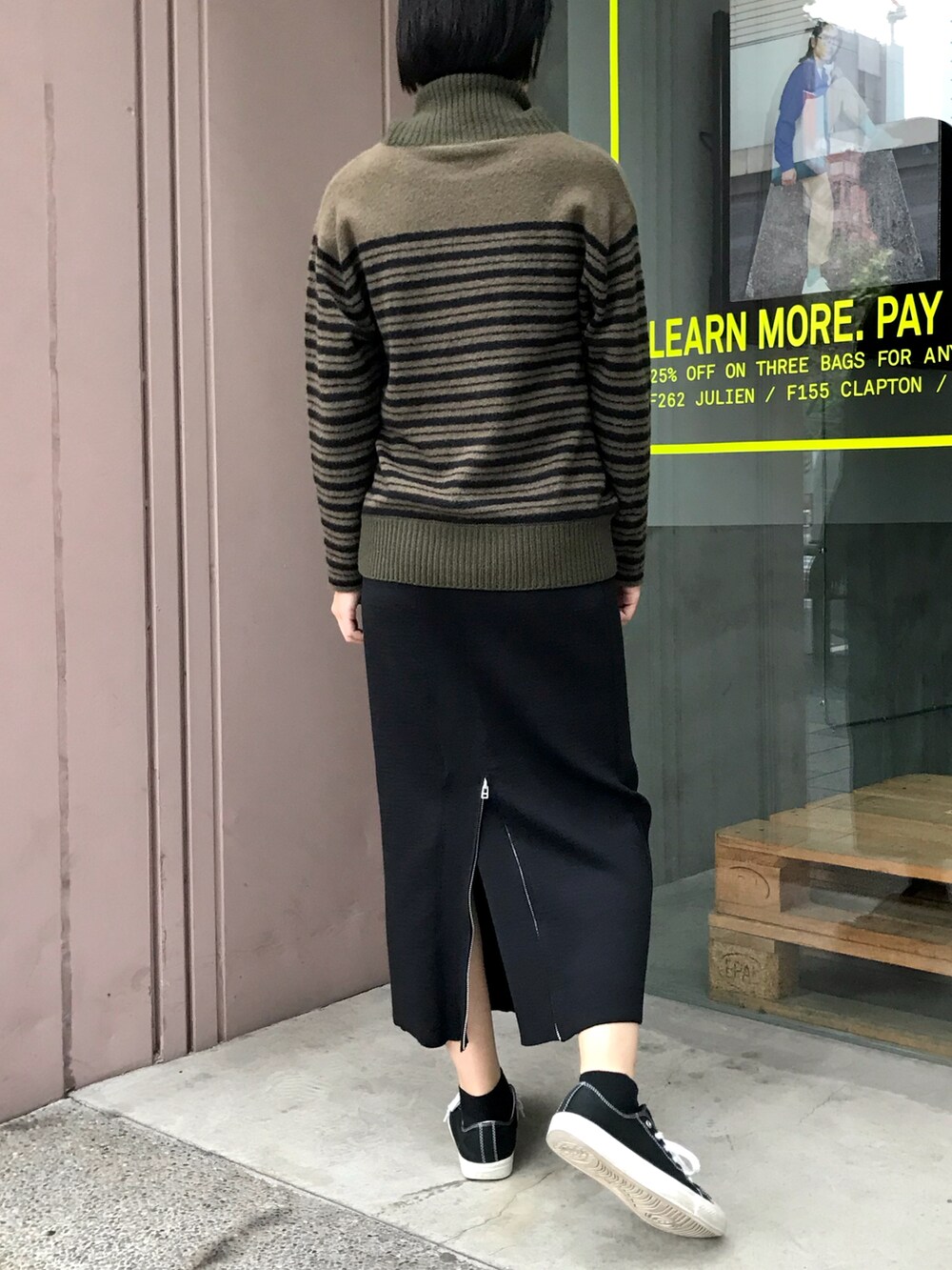 グリーン系のニット/セーター、ブラック系のスカートを着用したレディースの冬コーディネートの2枚目の写真