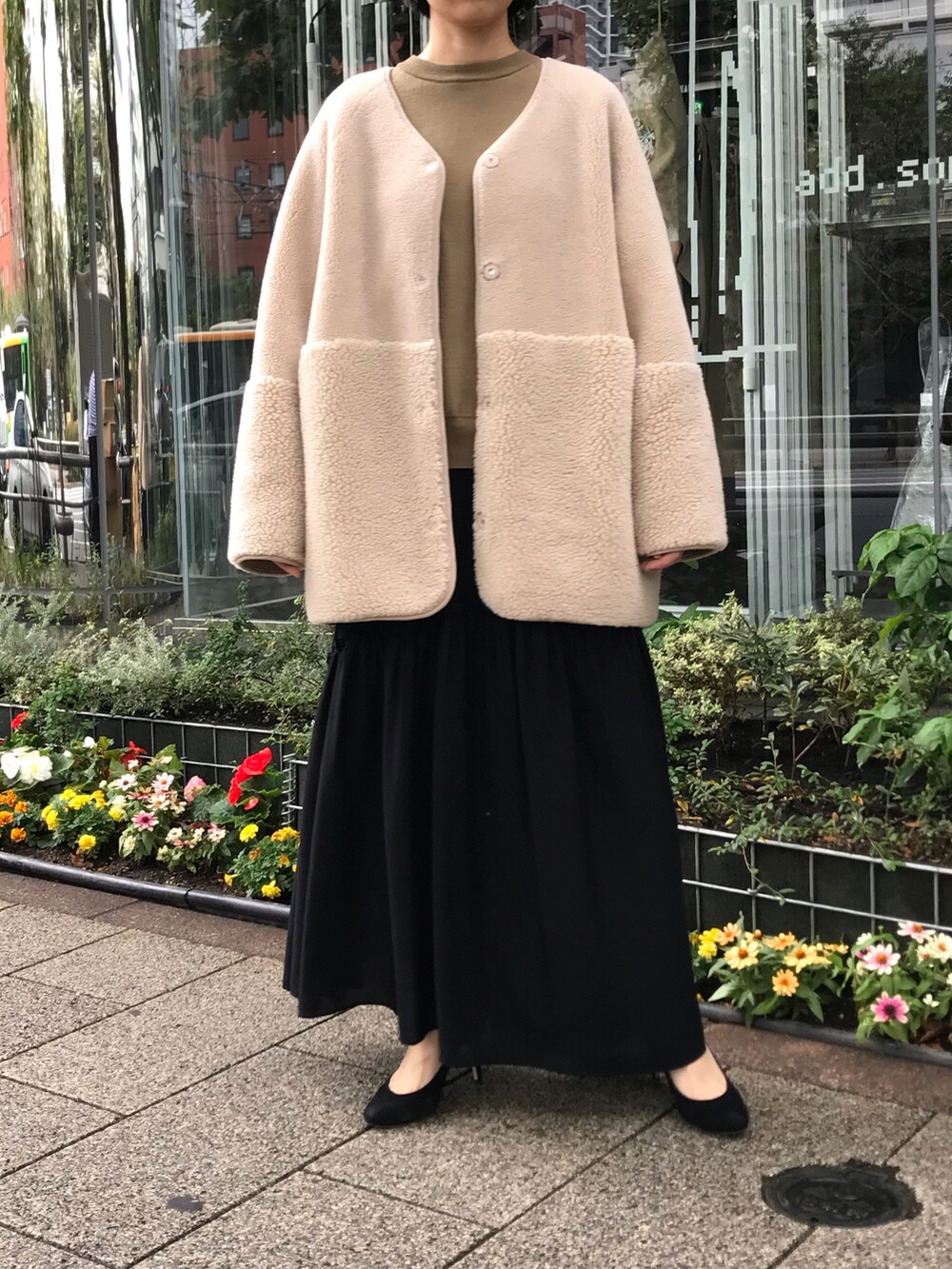 ブラック系のスカート、ベージュ系のムートンコートを着用したレディースの秋コーディネートの2枚目の写真