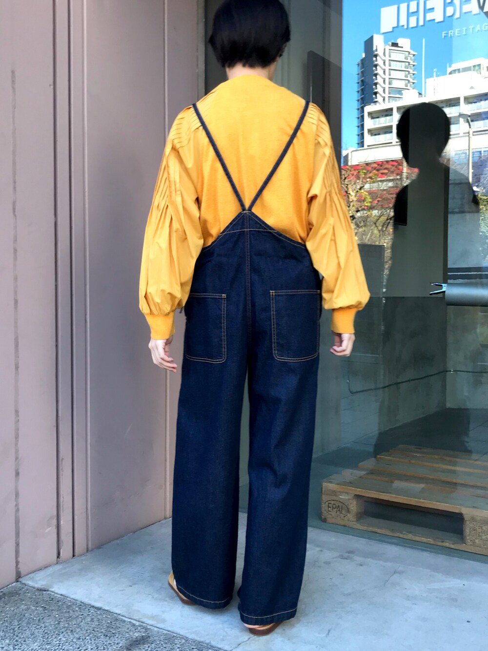 オレンジ系のニット/セーター、ブルー系のサロペット/オーバーオールを着用したレディースの冬コーディネートの2枚目の写真