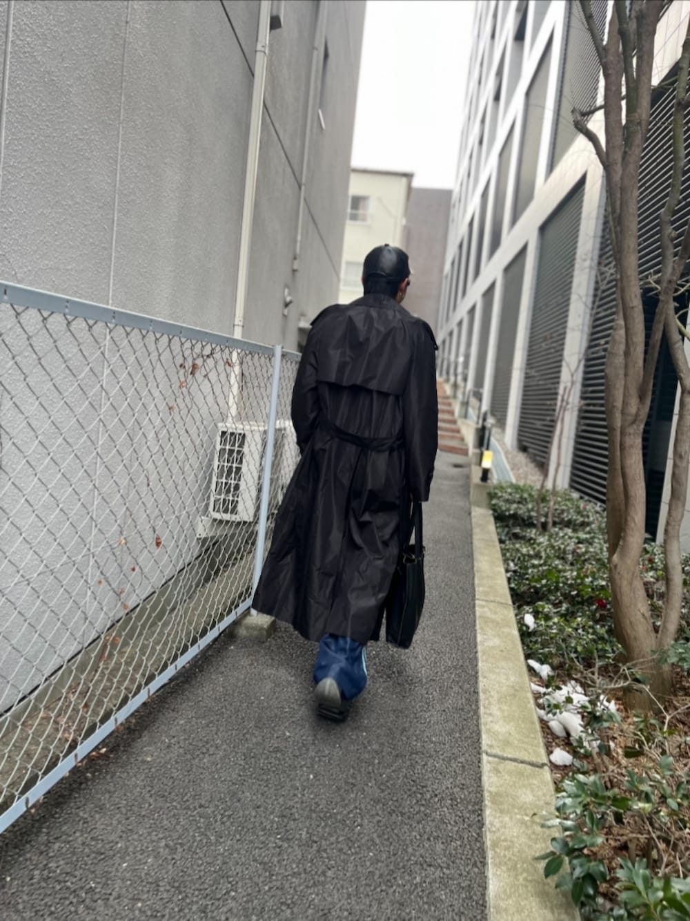 ブラック系のステンカラーコート、ピンク系のTシャツ/カットソー、ブルー系のその他パンツを着用したメンズの冬コーディネートの4枚目の写真