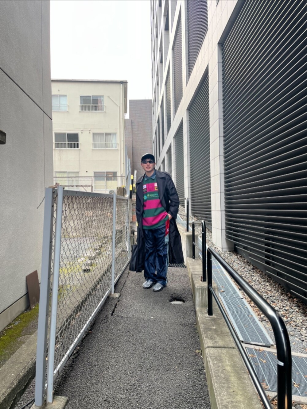 ブラック系のステンカラーコート、ピンク系のTシャツ/カットソー、ブルー系のその他パンツを着用したメンズの冬コーディネートの3枚目の写真