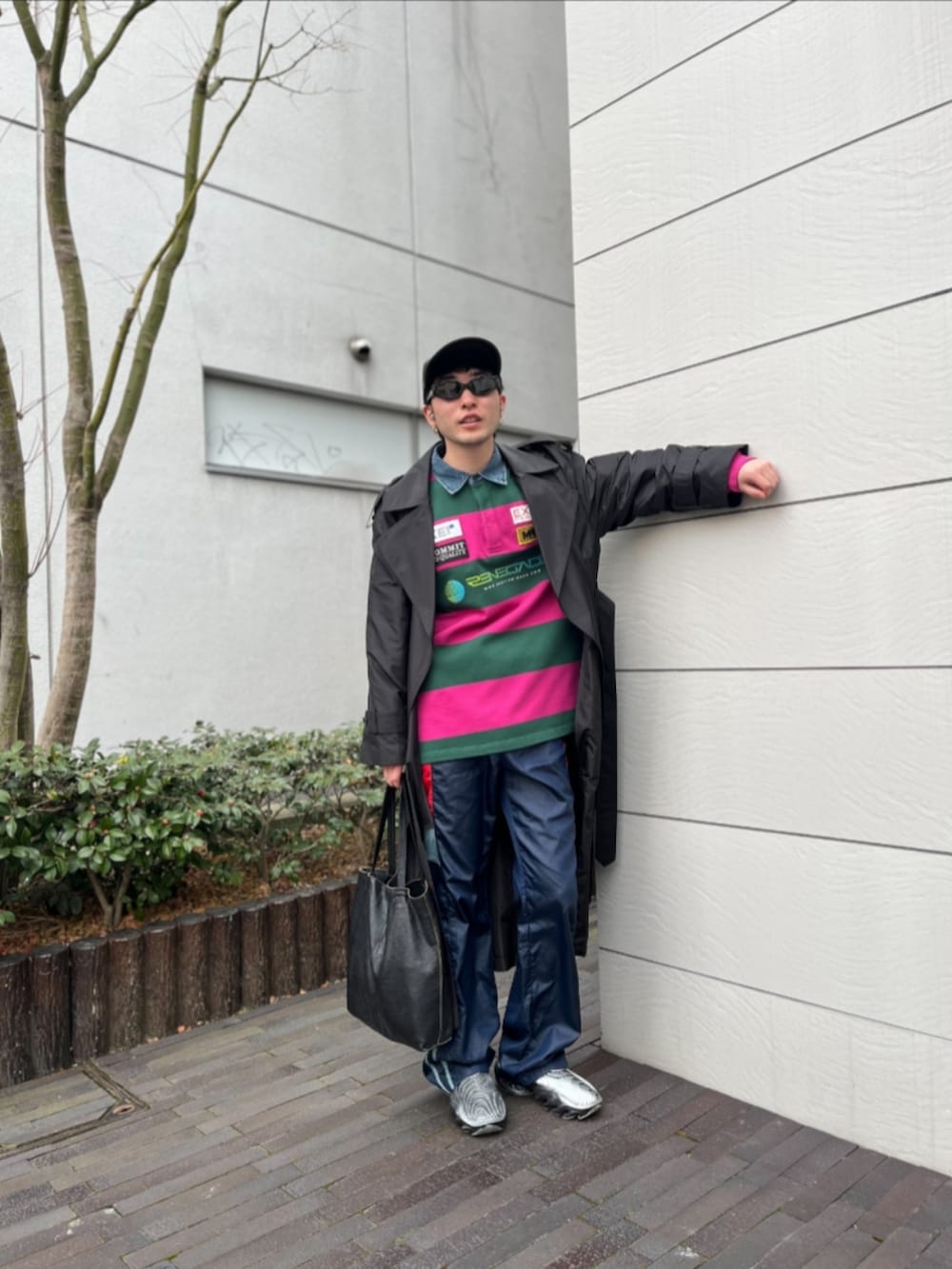 ブラック系のステンカラーコート、ピンク系のTシャツ/カットソー、ブルー系のその他パンツを着用したメンズの冬コーディネートの2枚目の写真