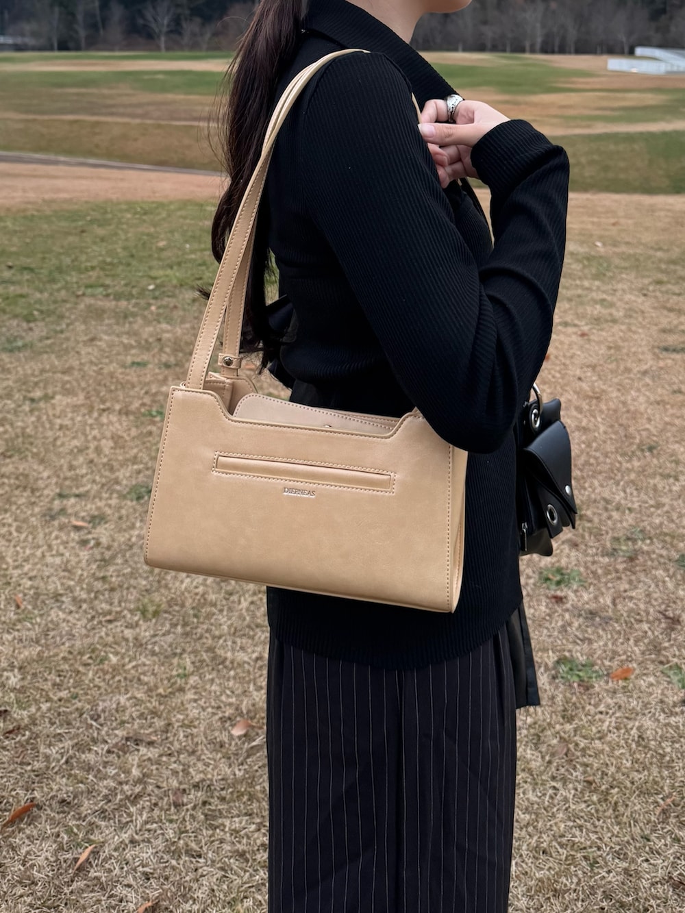 ブラック系のスラックス、イエロー系のハンドバッグ、ブラック系のスニーカーを着用したレディースの秋コーディネートの2枚目の写真