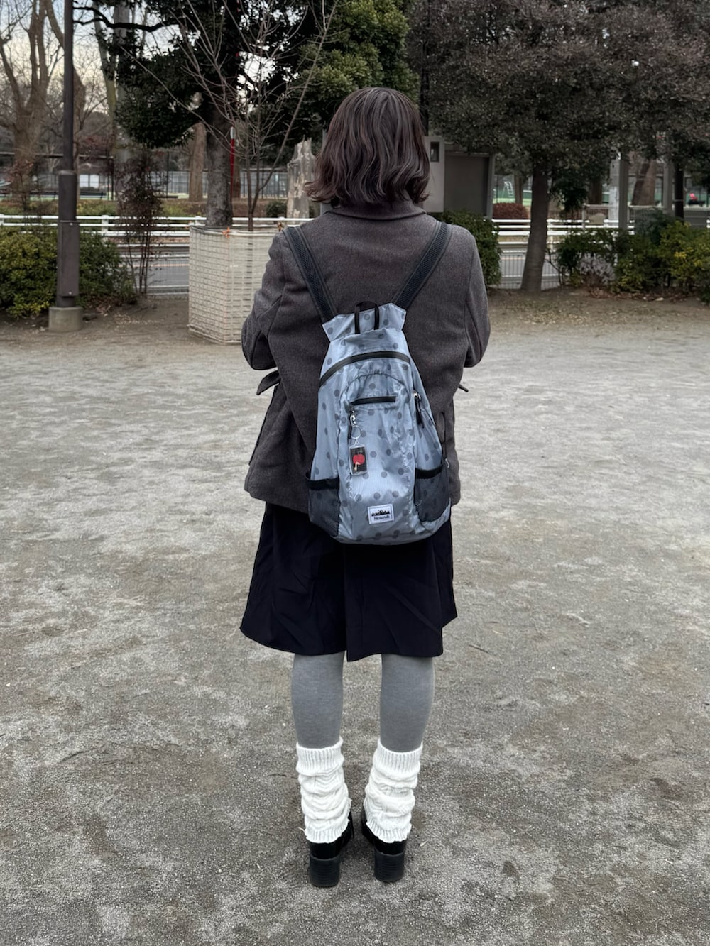 グレー系のダッフルコート、グレー系のバックパック/リュック、ブラック系のスカートを着用したレディースの冬コーディネートの2枚目の写真