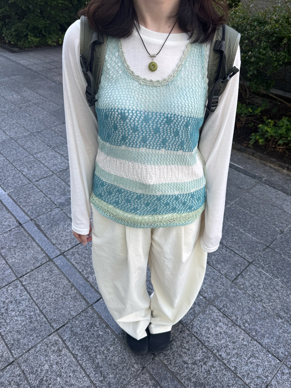ホワイト系のスラックス、ホワイト系のTシャツ/カットソー、ブラック系のサンダルを着用したレディースの夏コーディネートの2枚目の写真