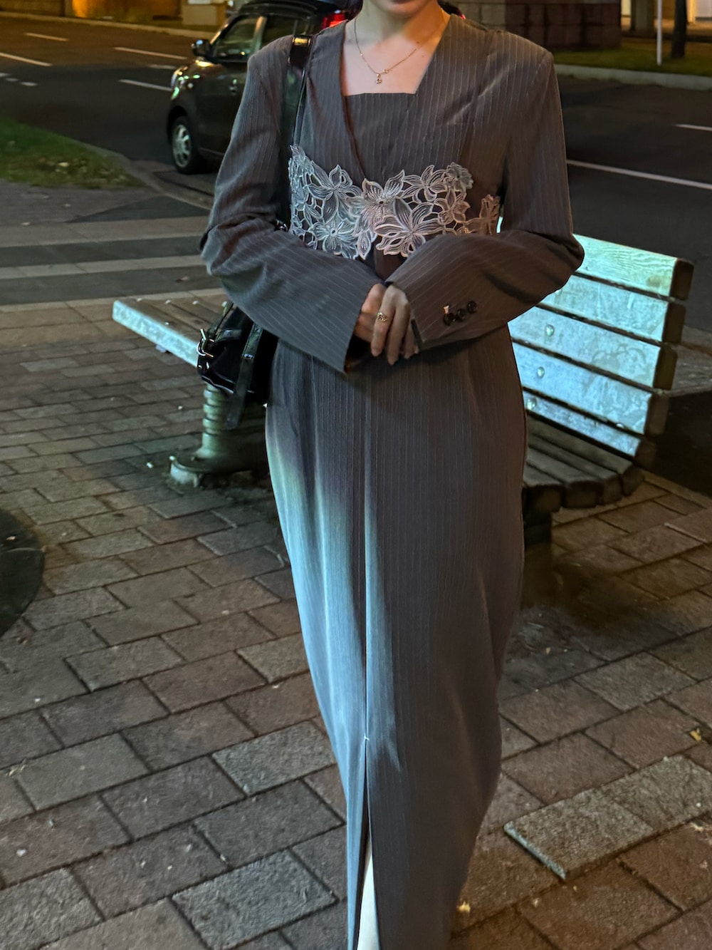 グレー系のドレス、ブラック系のパンプス、ブラック系のショルダーバッグを着用したレディースの秋コーディネートの2枚目の写真