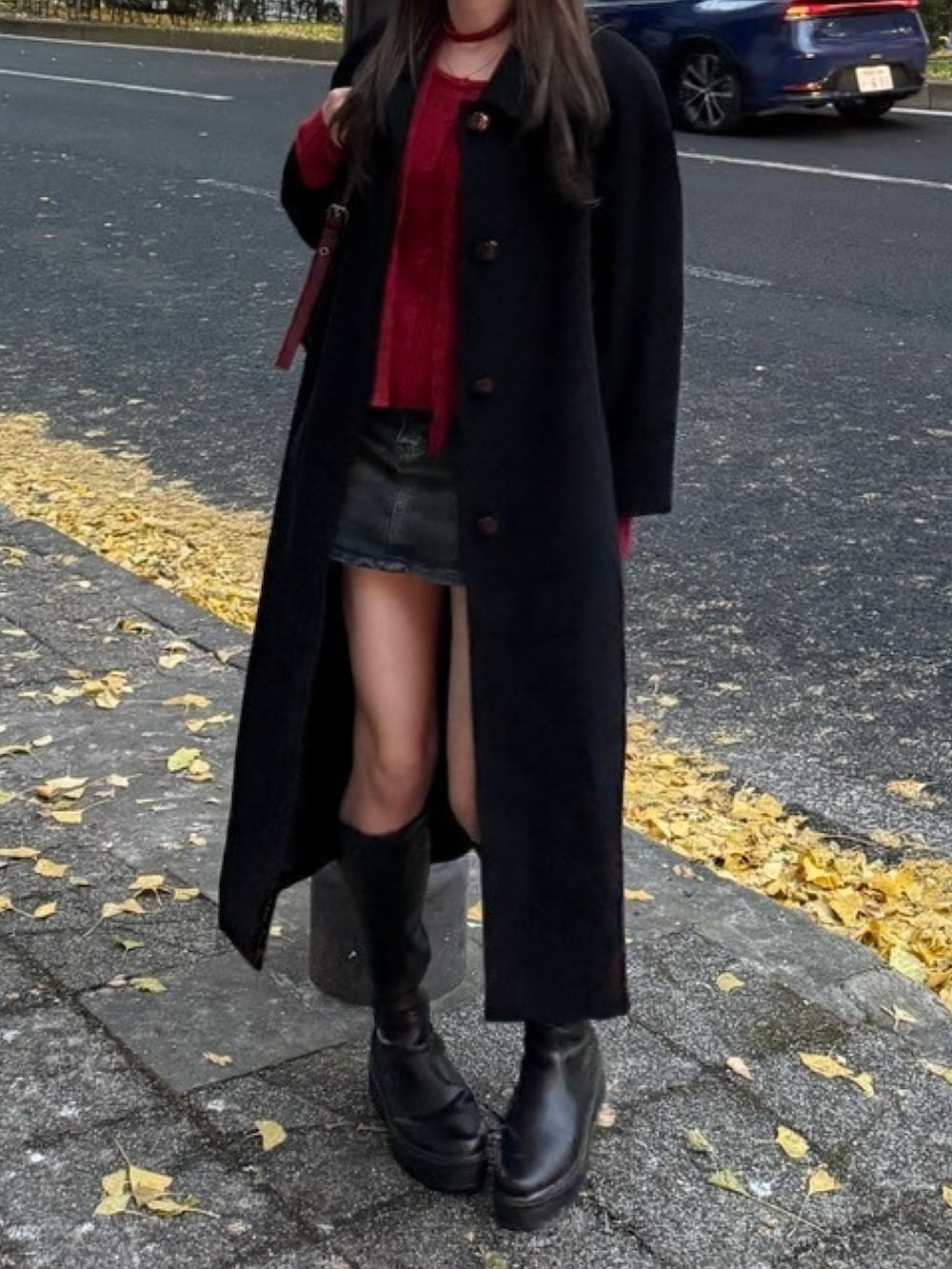 レッド系のニット/セーター、ブルー系のデニムスカート、レッド系のハンドバッグを着用したレディースの秋コーディネートの3枚目の写真