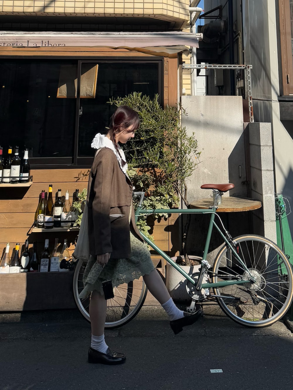 ブラウン系のローファー、ブラウン系のテーラードジャケット、グリーン系のワンピースを着用したレディースの秋コーディネートの2枚目の写真