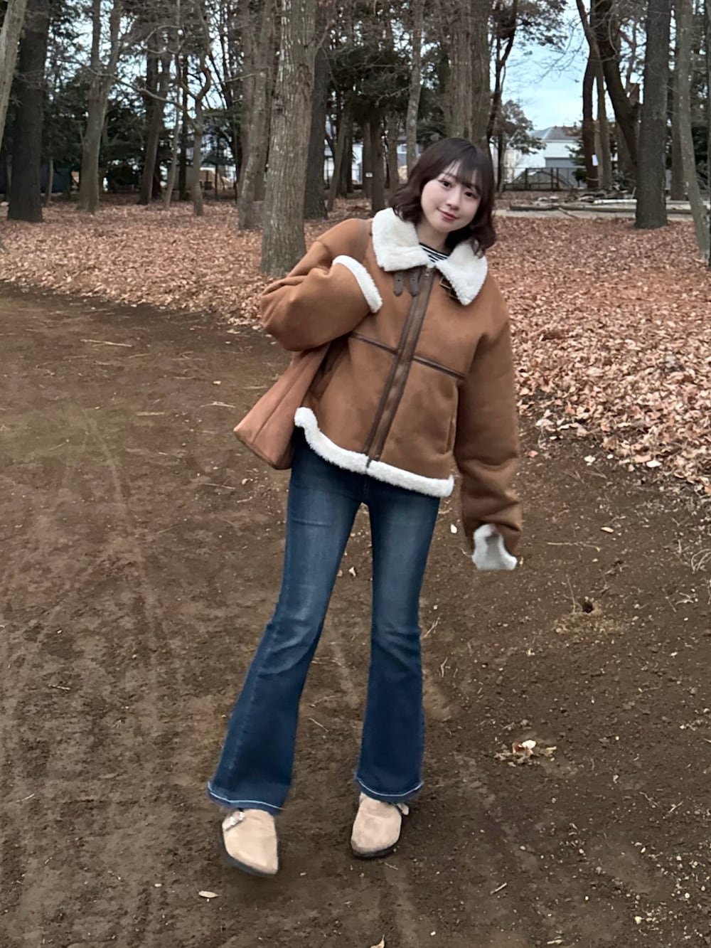 イエロー系のブルゾン、ブラウン系のサンダル、ブラウン系のトートバッグを着用したレディースの冬コーディネートの2枚目の写真