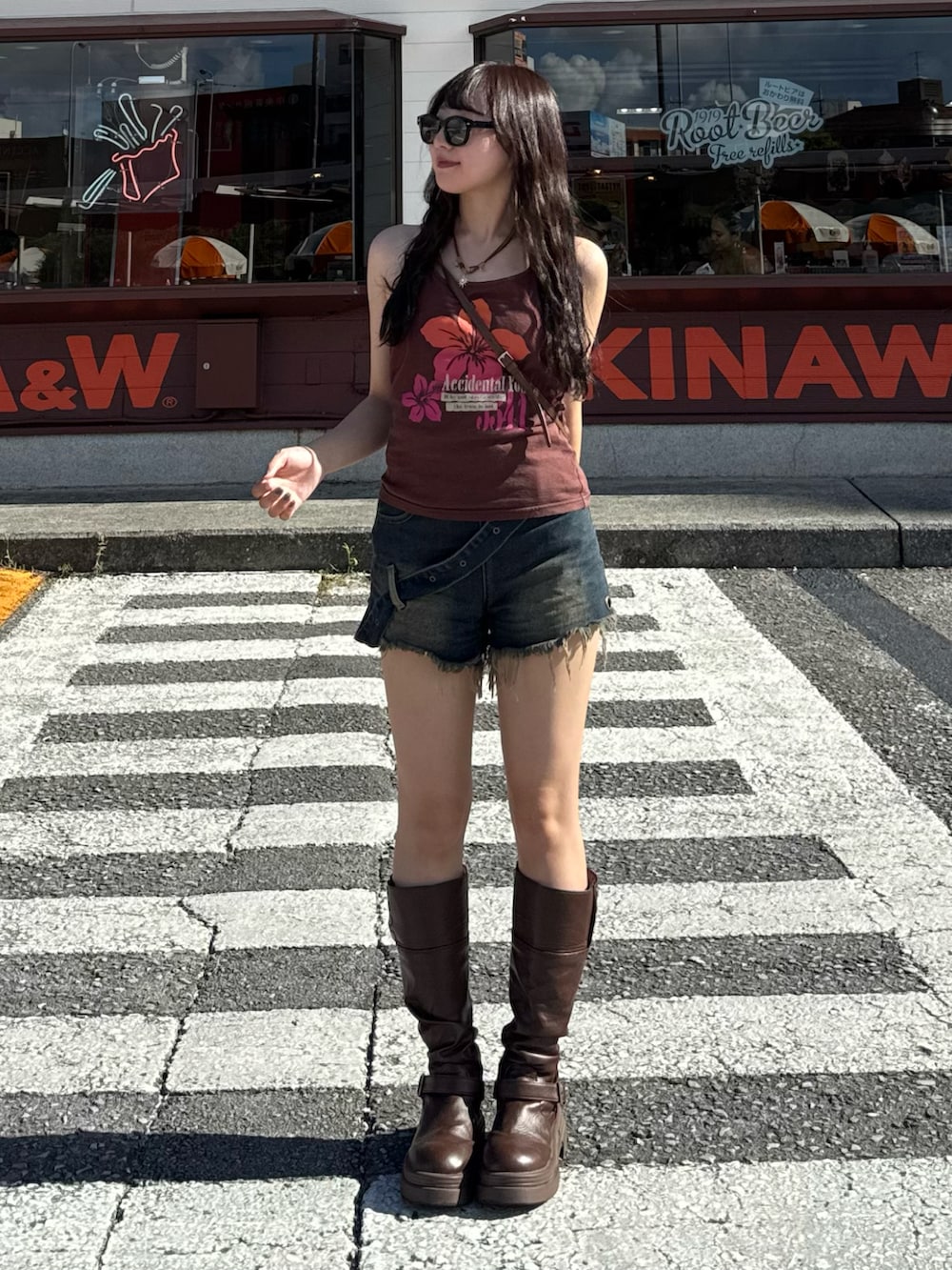 ブラウン系のブーツ、ブラウン系のショルダーバッグ、ブルー系のデニムパンツを着用したレディースの夏コーディネートの2枚目の写真