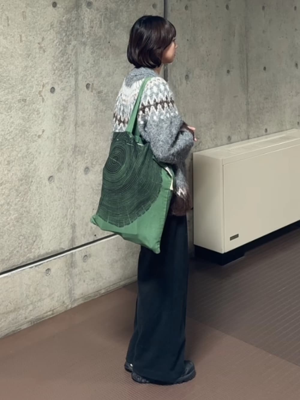 グレー系のニット/セーター、グレー系のスラックス、グリーン系のトートバッグを着用したレディースの冬コーディネートの2枚目の写真