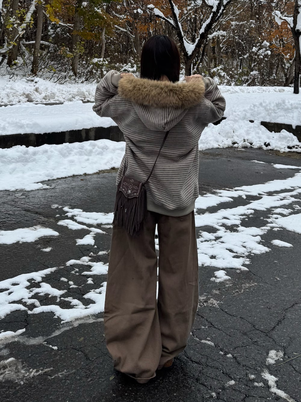 ブラウン系のデニムパンツ、ブラウン系のサンダル、ベージュ系のパーカーを着用したレディースの秋コーディネートの3枚目の写真