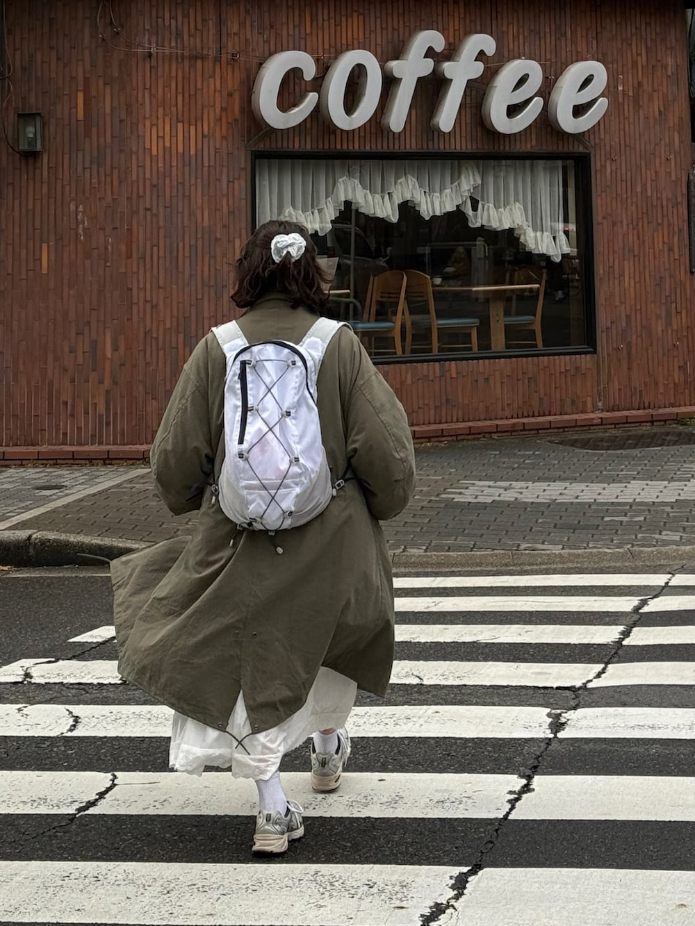 グリーン系のモッズコート、シルバー系のスニーカー、ホワイト系のバックパック/リュックを着用したレディースの冬コーディネートの2枚目の写真