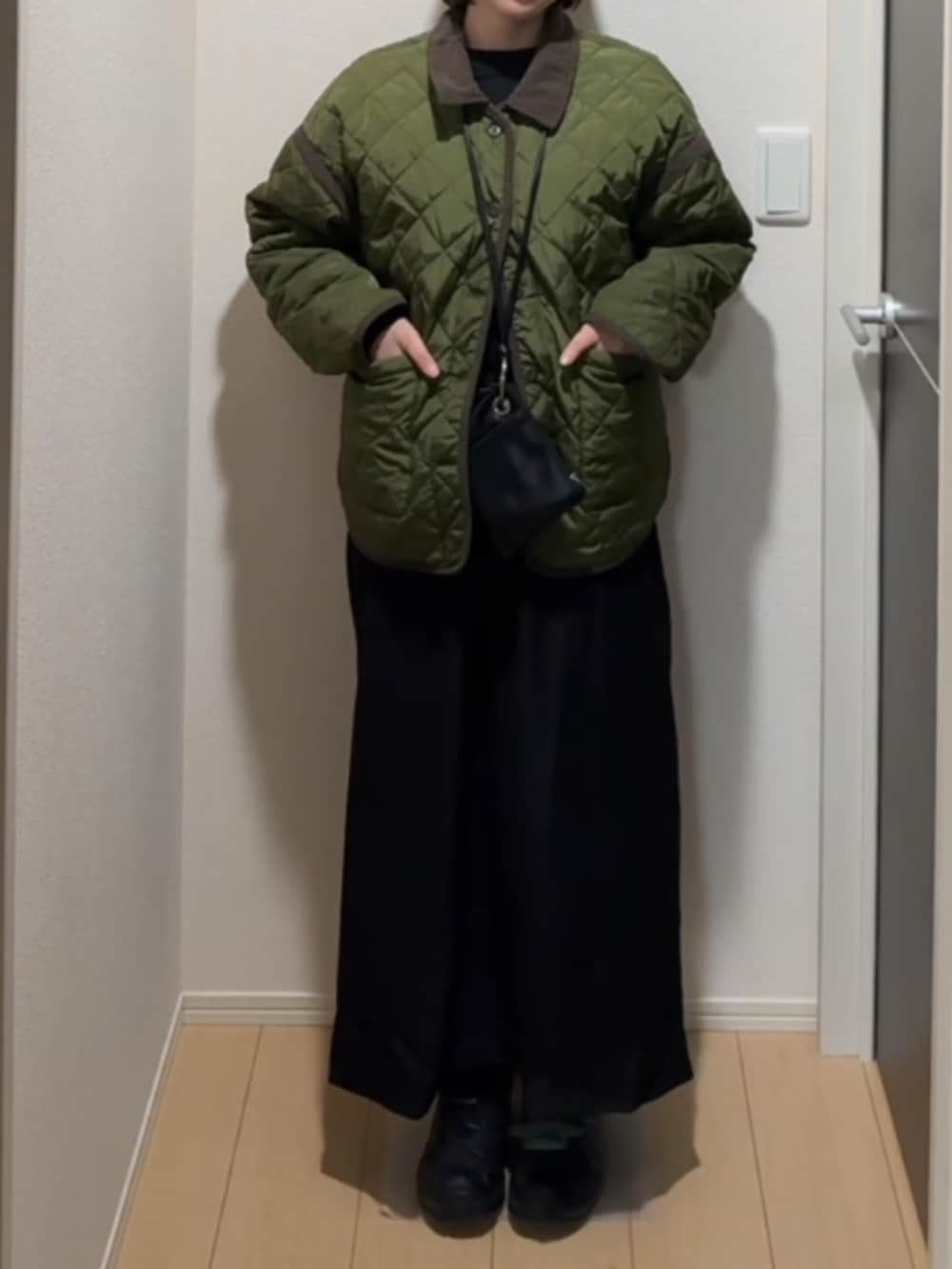 ブラック系のショルダーバッグ、ブラック系のスニーカー、グリーン系のジャケット/アウターを着用したレディースの冬コーディネートの2枚目の写真