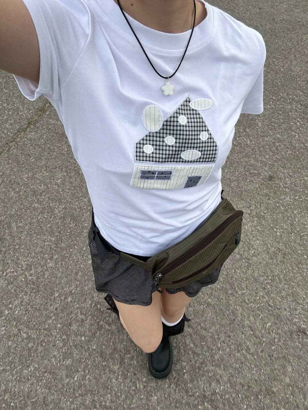 ホワイト系のTシャツ/カットソー、ブラック系のパンツ、グリーン系のボディバッグ/ウエストポーチを着用したレディースの春コーディネートの2枚目の写真