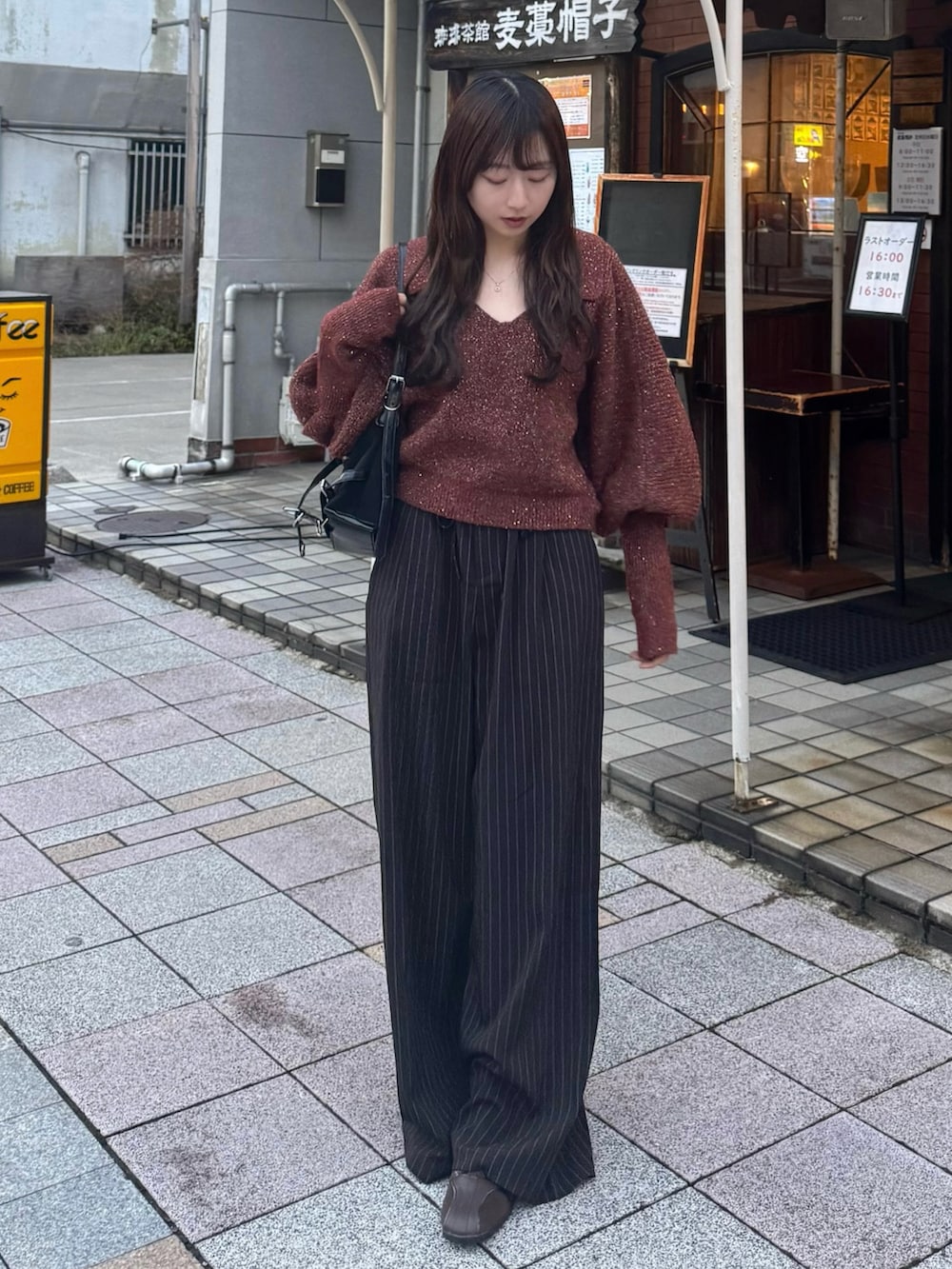 ブラウン系のニット/セーター、ブラック系のスラックス、ブラウン系のスニーカーを着用したレディースの秋コーディネートの2枚目の写真