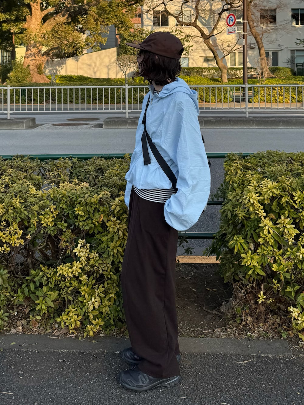 ブラウン系のボディバッグ/ウエストポーチ、ブラック系のスニーカー、ホワイト系のTシャツ/カットソーを着用したレディースの冬コーディネートの2枚目の写真