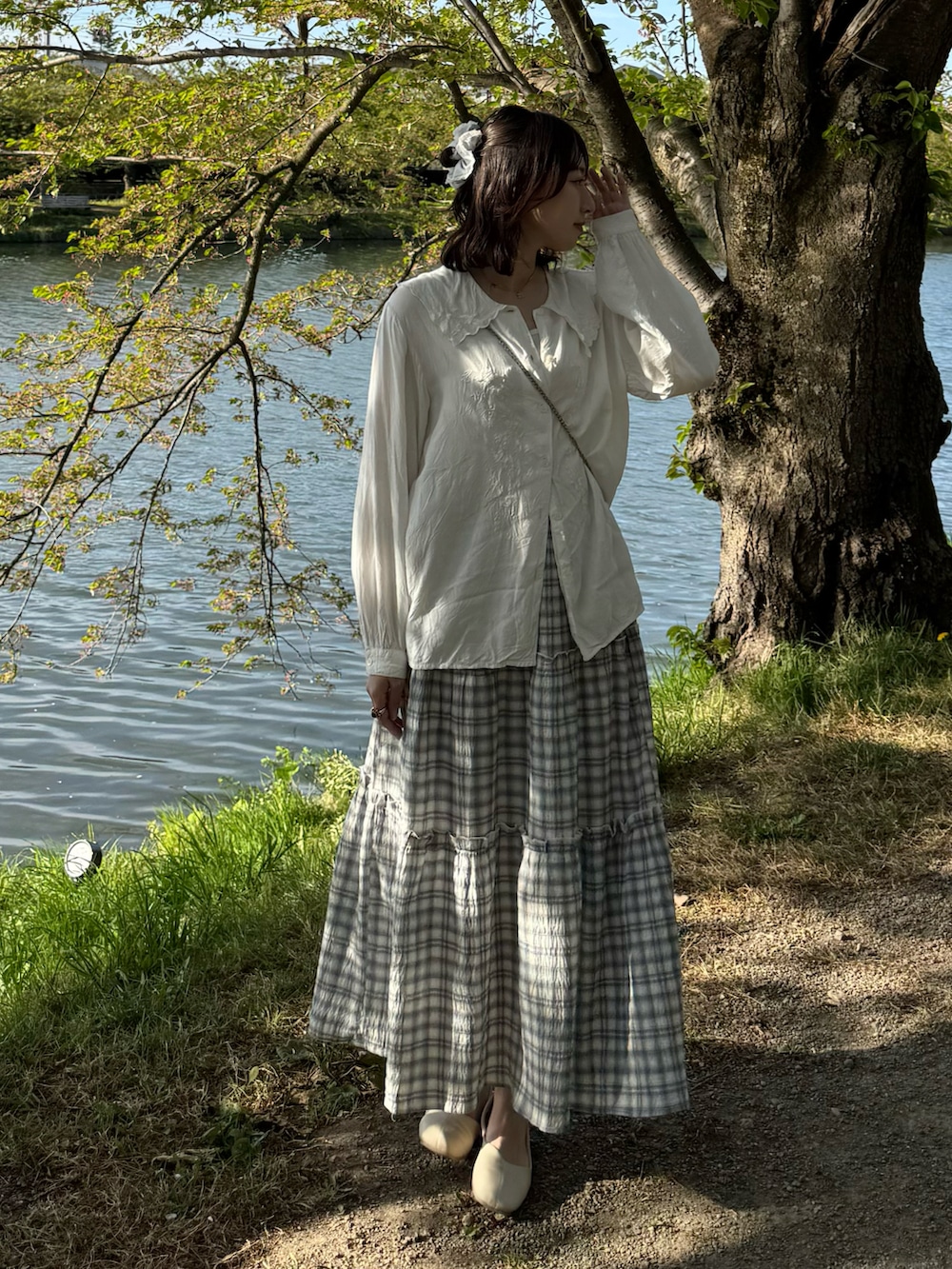 ブルー系のスカート、ホワイト系のパンプス、ピンク系のショルダーバッグを着用したレディースの春コーディネートの3枚目の写真