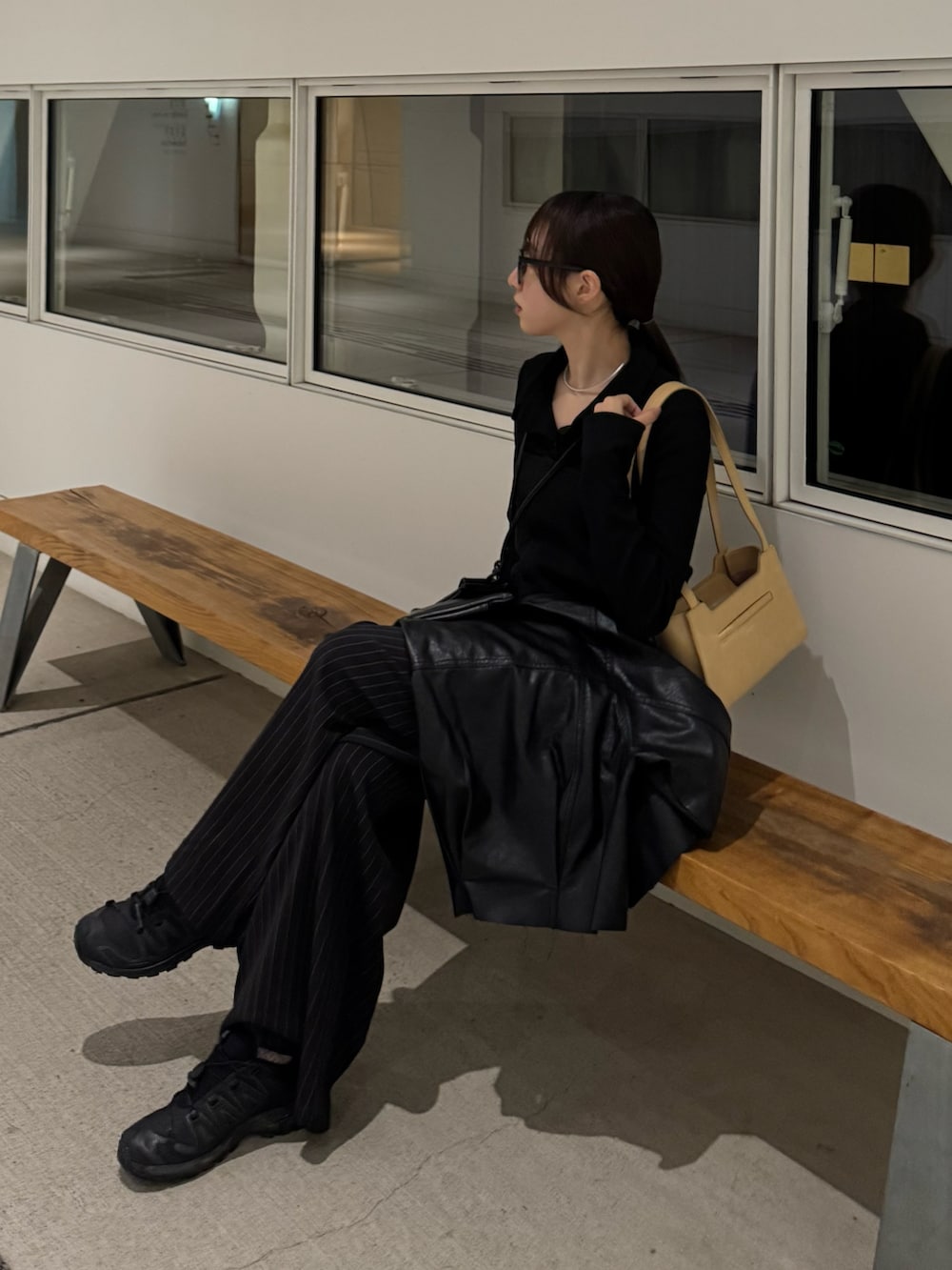 ブラック系のスラックス、イエロー系のハンドバッグ、ブラック系のスニーカーを着用したレディースの秋コーディネートの3枚目の写真