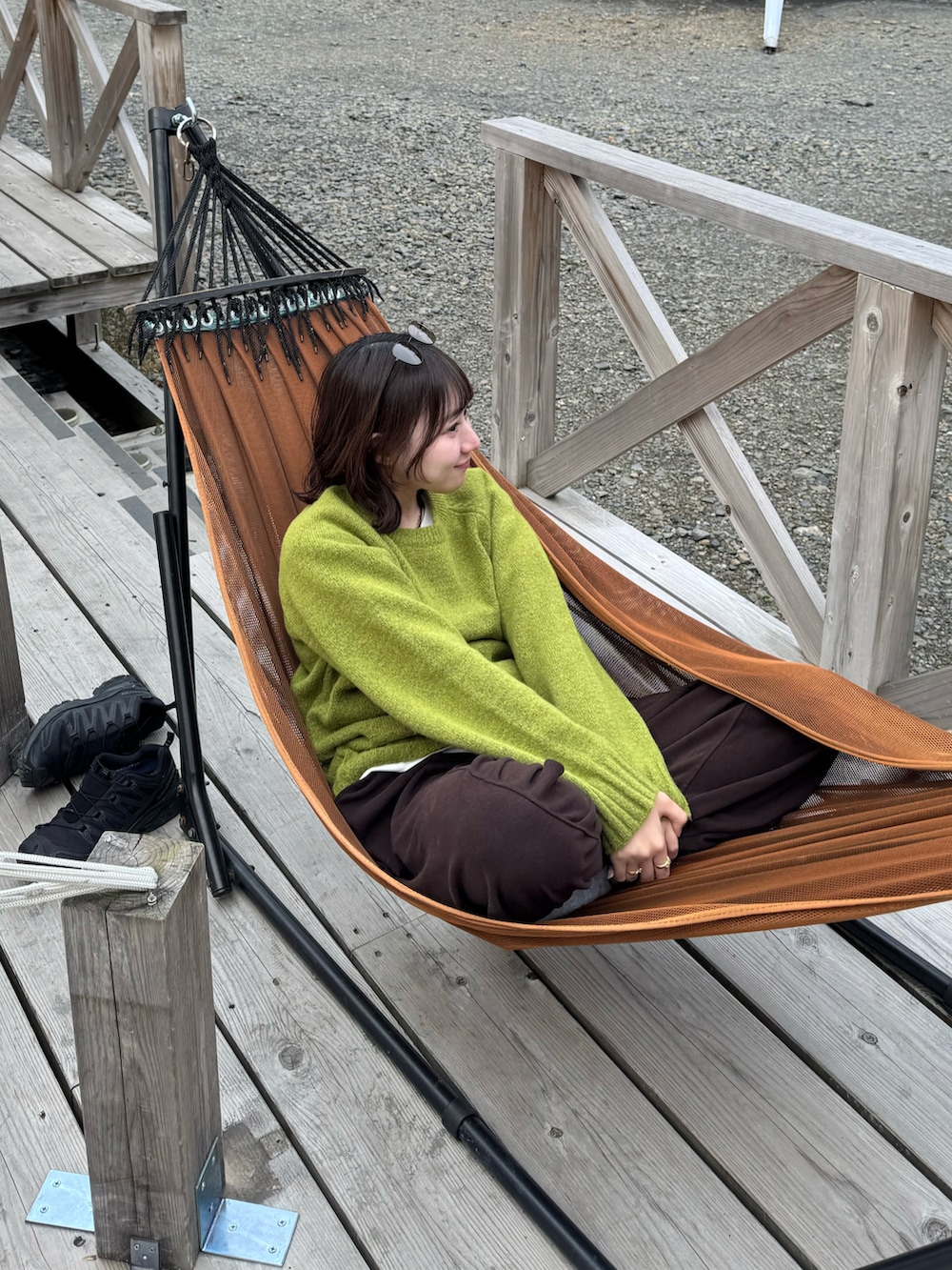 グリーン系のニット/セーター、ブラウン系のボディバッグ/ウエストポーチ、ブラック系のスニーカーを着用したレディースの春コーディネートの2枚目の写真