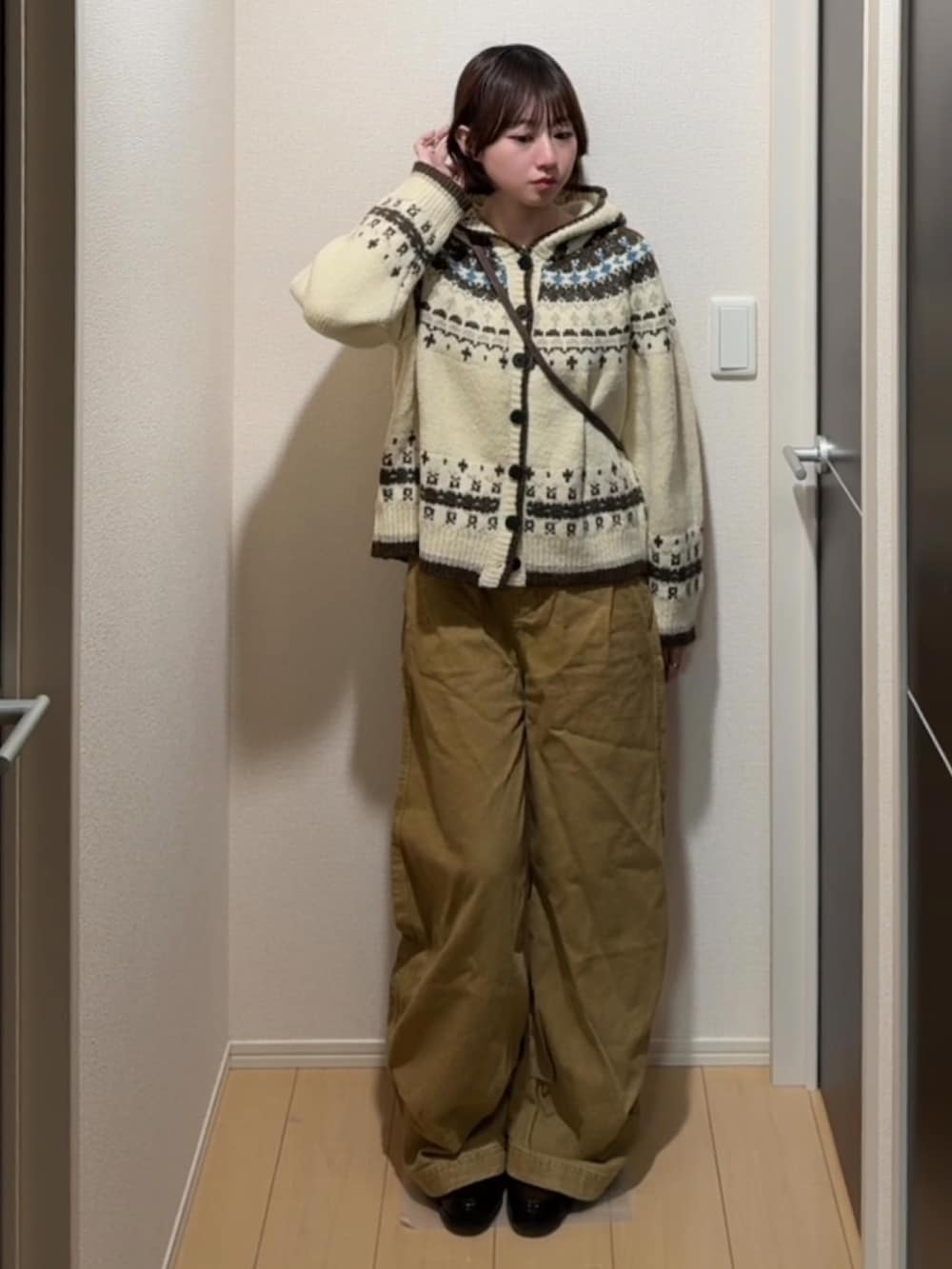 ホワイト系のニット/セーター、ブラウン系のデニムパンツ、ブラウン系のローファーを着用したレディースの冬コーディネートの2枚目の写真