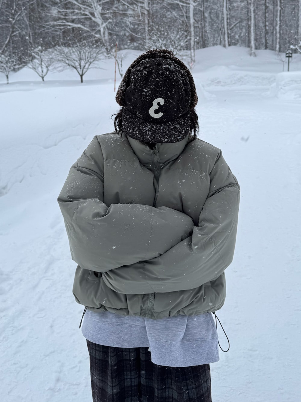 グリーン系のダウンジャケット/コート、グレー系のスウェット、ブラウン系のパンツを着用したレディースの冬コーディネートの2枚目の写真