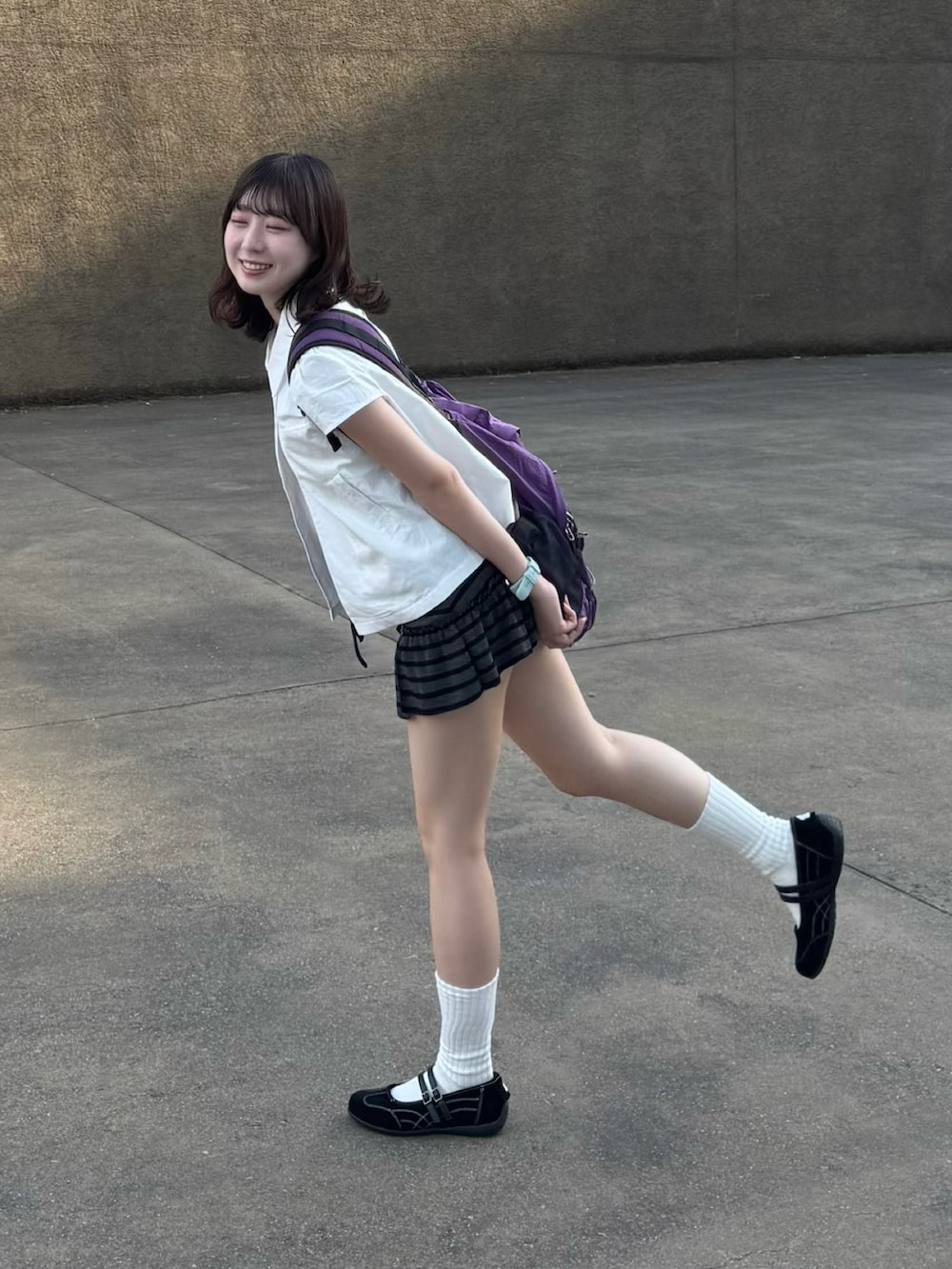 ブラック系のスニーカー、パープル系のバッグ、ホワイト系のTシャツ/カットソーを着用したレディースの夏コーディネートの3枚目の写真