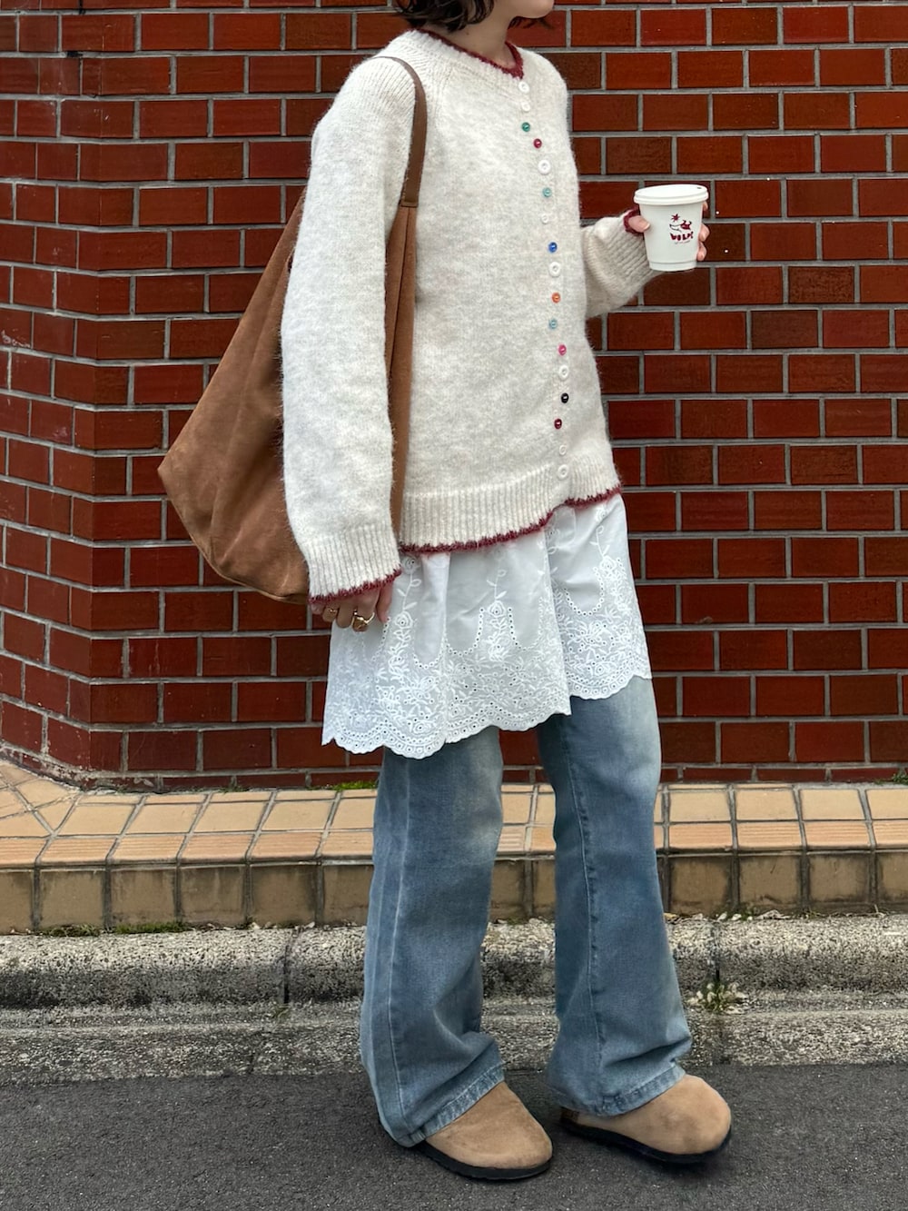 ホワイト系のニット/セーター、ホワイト系のワンピース/ドレス、ブルー系のデニムパンツを着用したレディースの春コーディネートの2枚目の写真